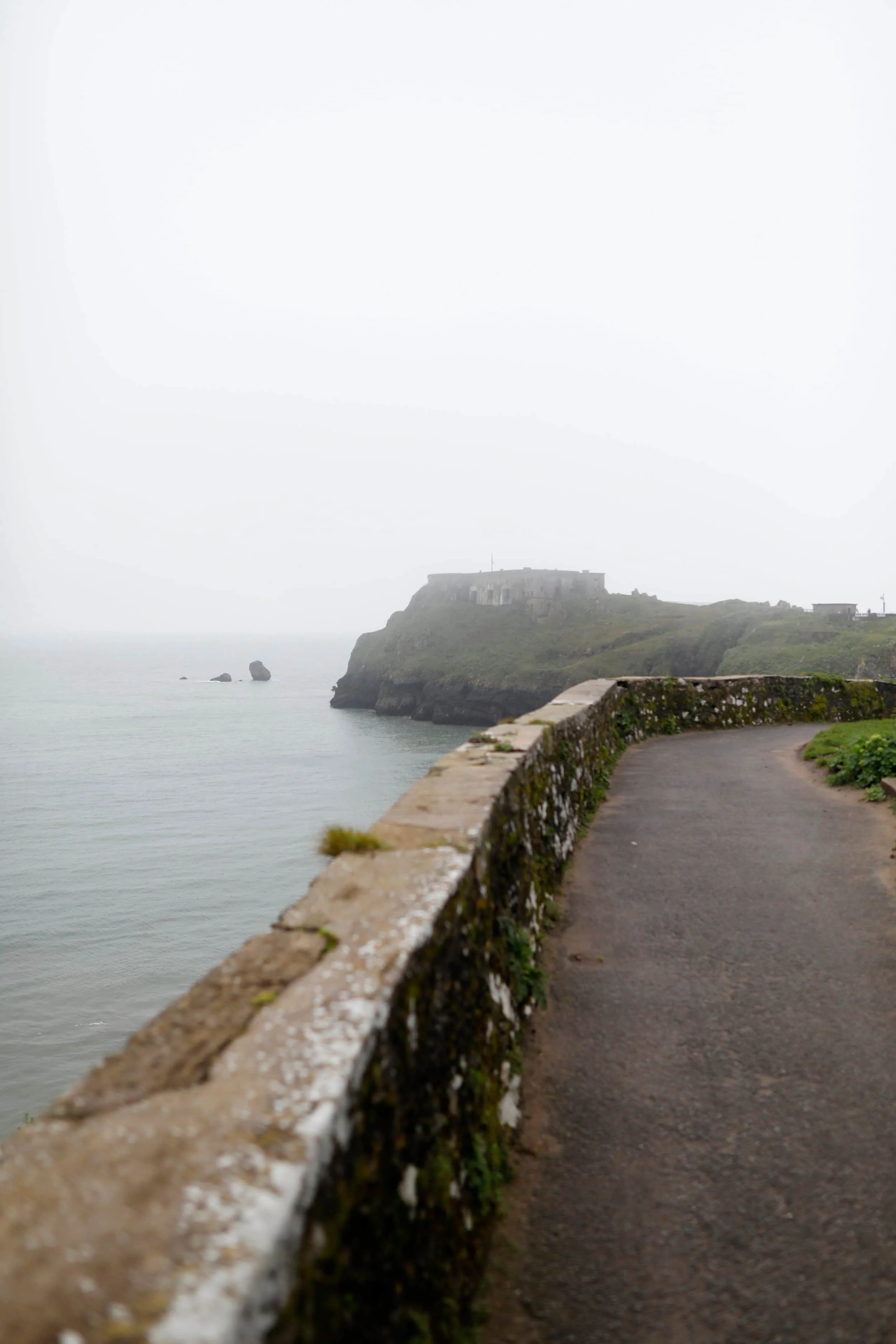 Foggy views from above of St. Catherine's Island and stone pathway in Tenby Wales
