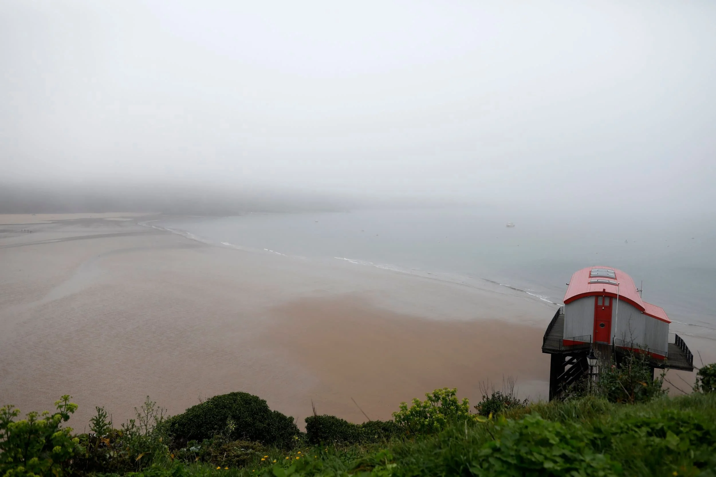 Foggy views from above of the ocean and beach in Tenby Wales