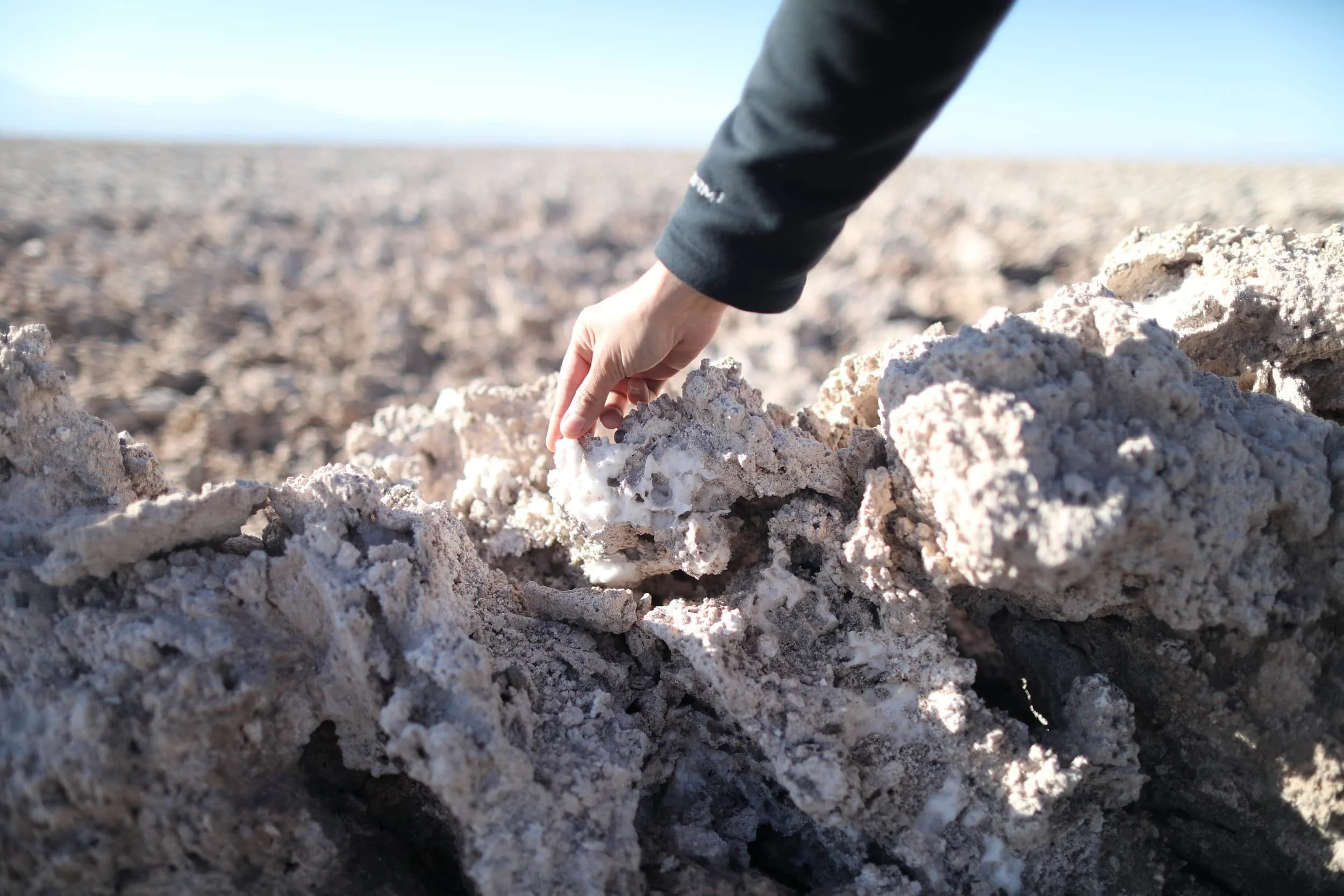 Hand touching crusty salt rocks at Chaxa Lagoon at Los Flamencos National Reserve near San Pedro de Atacama in Chile