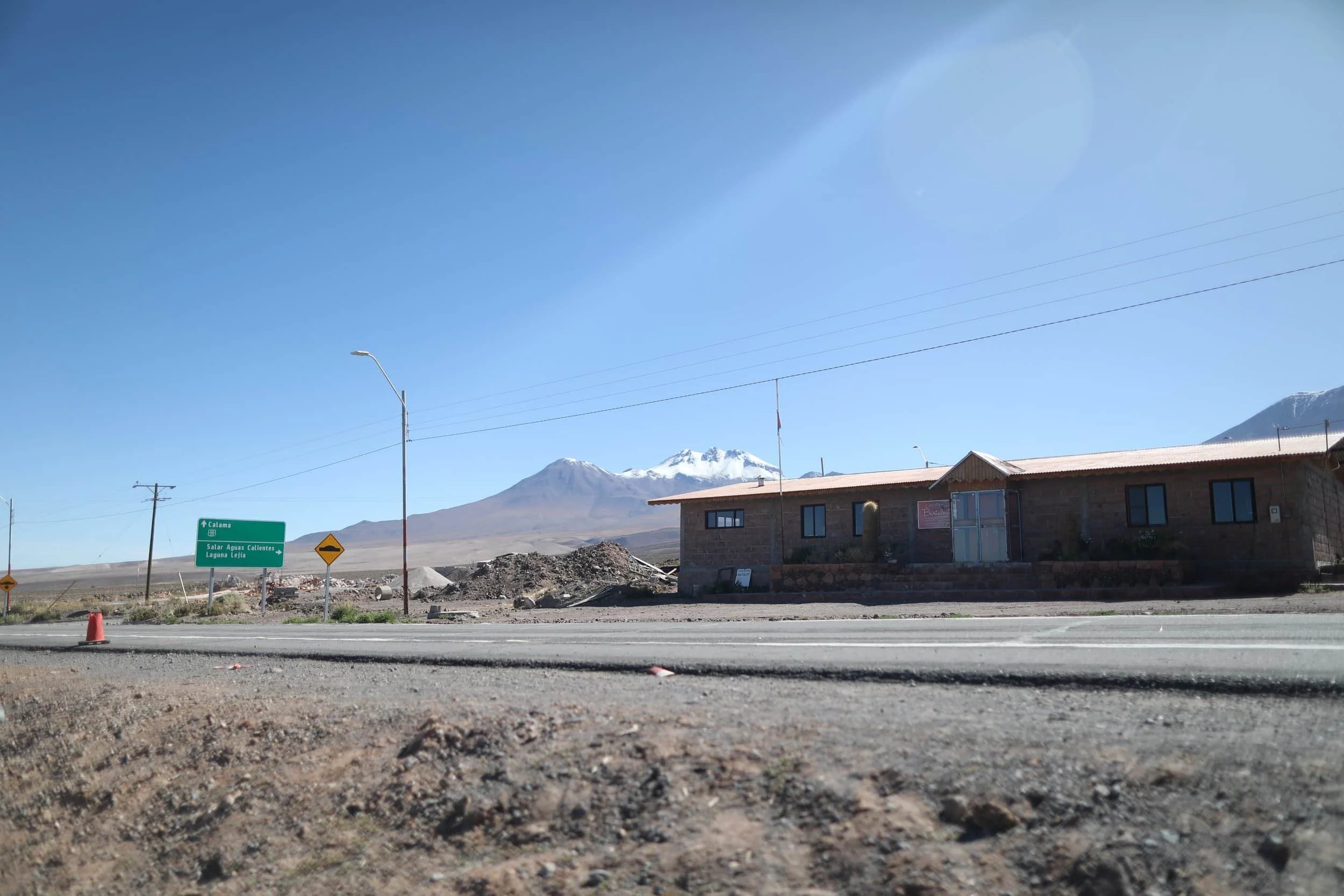 Street and building in front of large mountain with snow atop in Socaire in San Pedro de Atacama