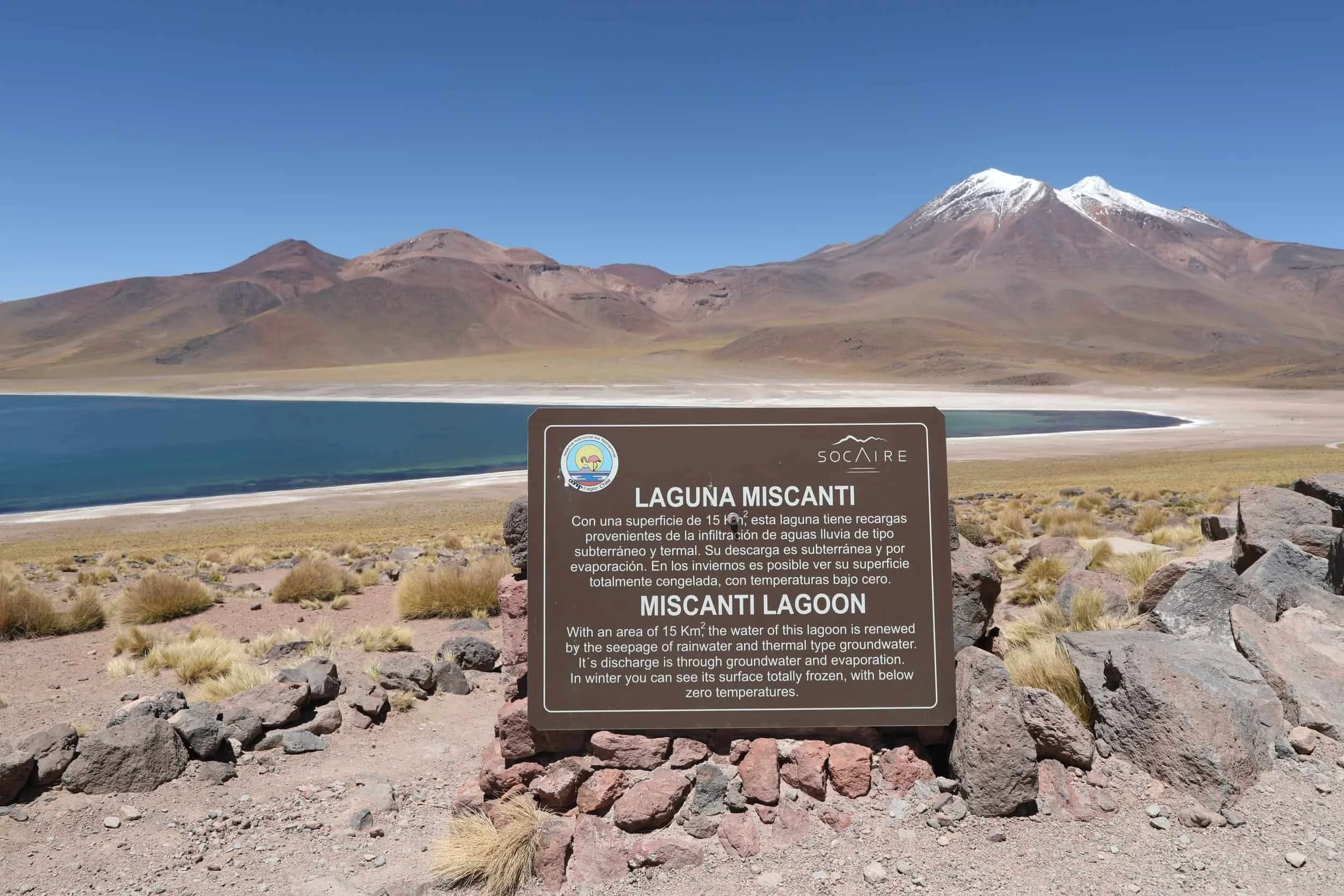 Signage in the deserts of Altiplanic Lagoon of Miscanti with snow topped mountains in the background