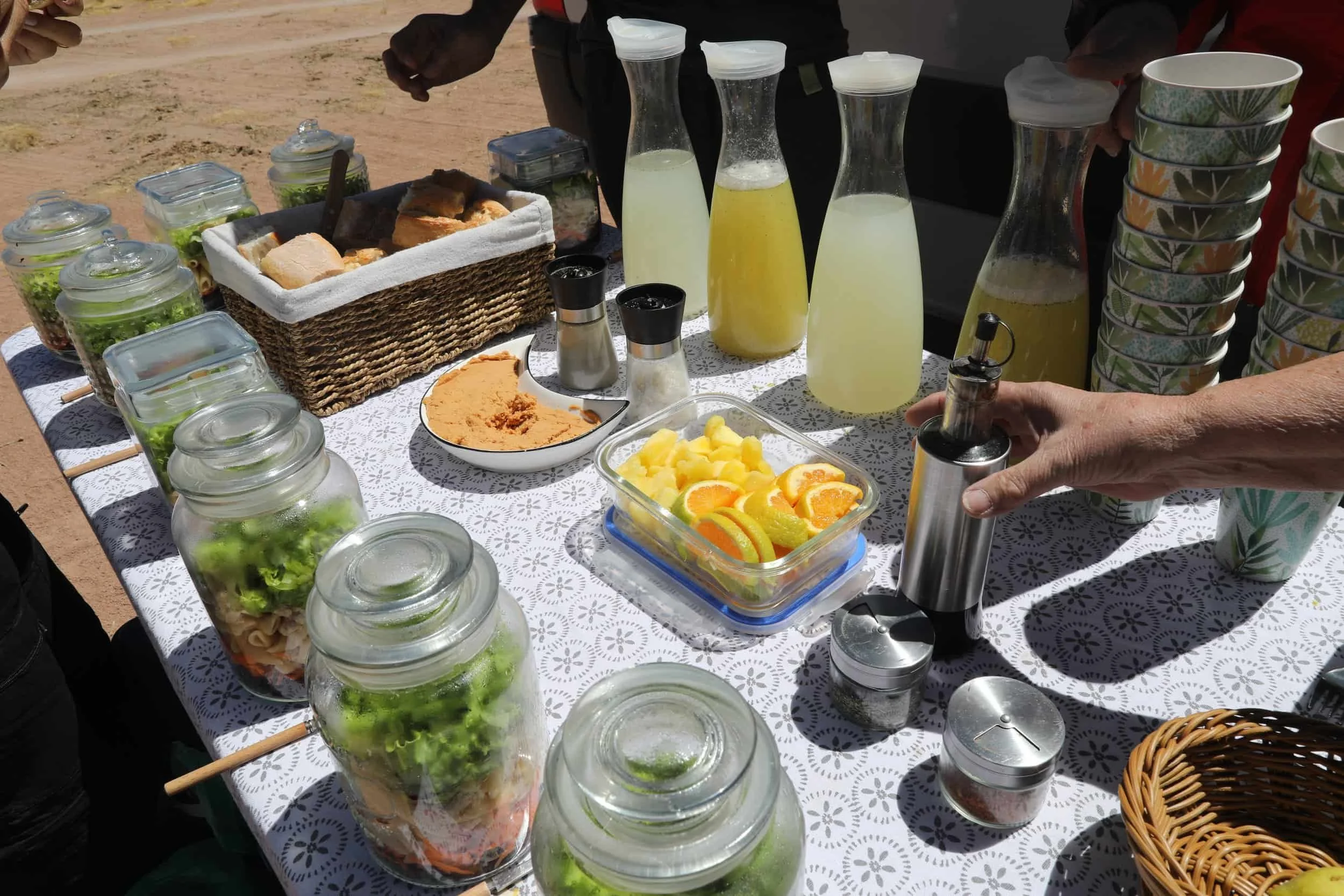 Table set up in the desert lined with mason jars filled with food and bottles of juice