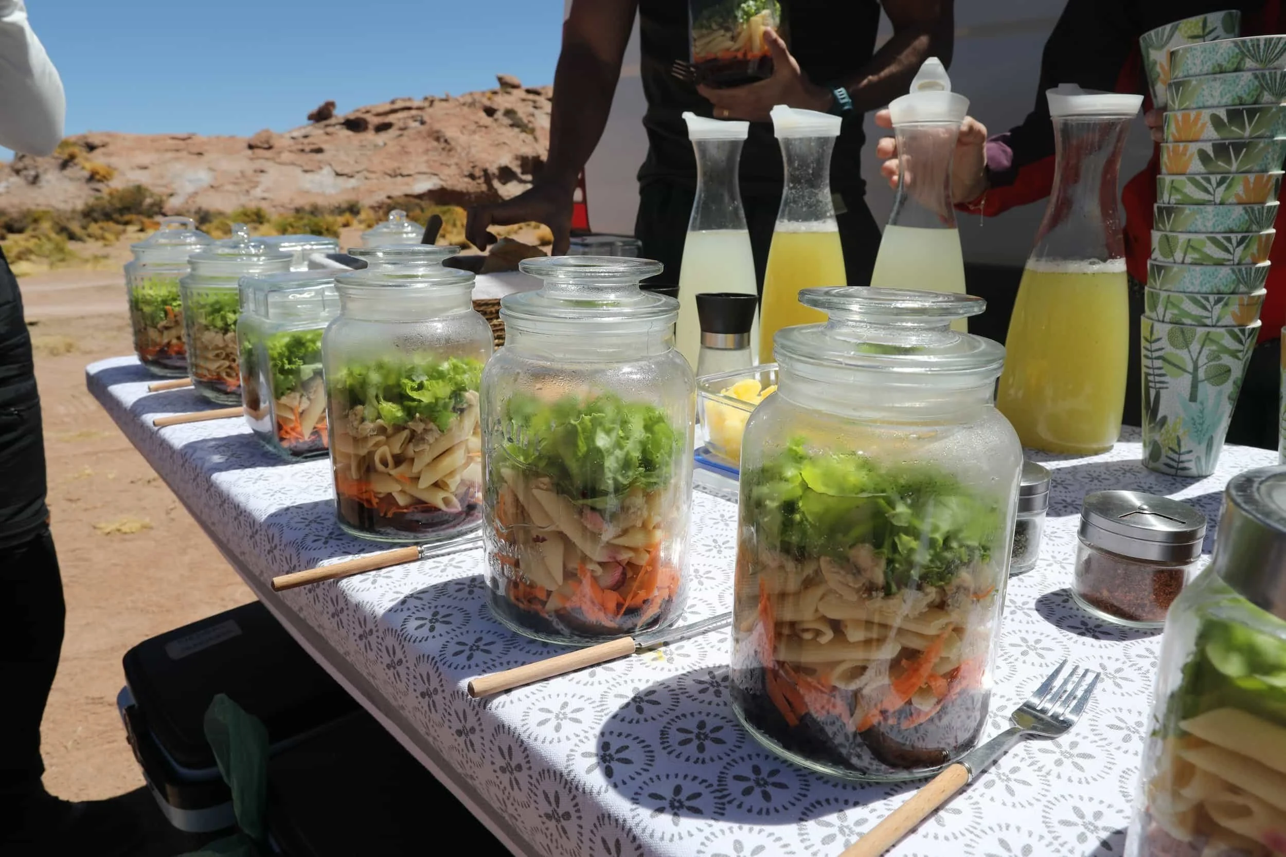 Table set up in the desert lined with mason jars filled with food and bottles of juice