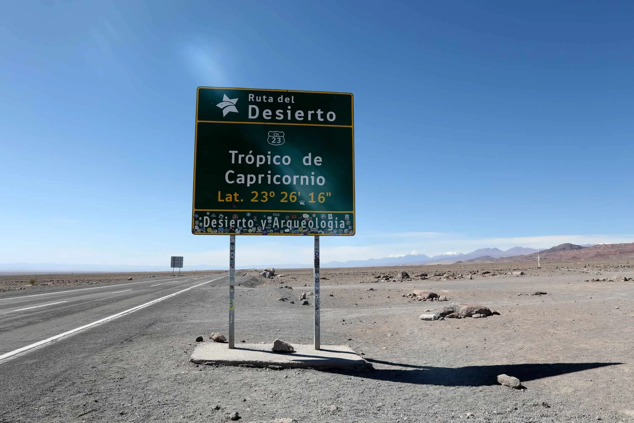 Large green sign on the side of a desert road