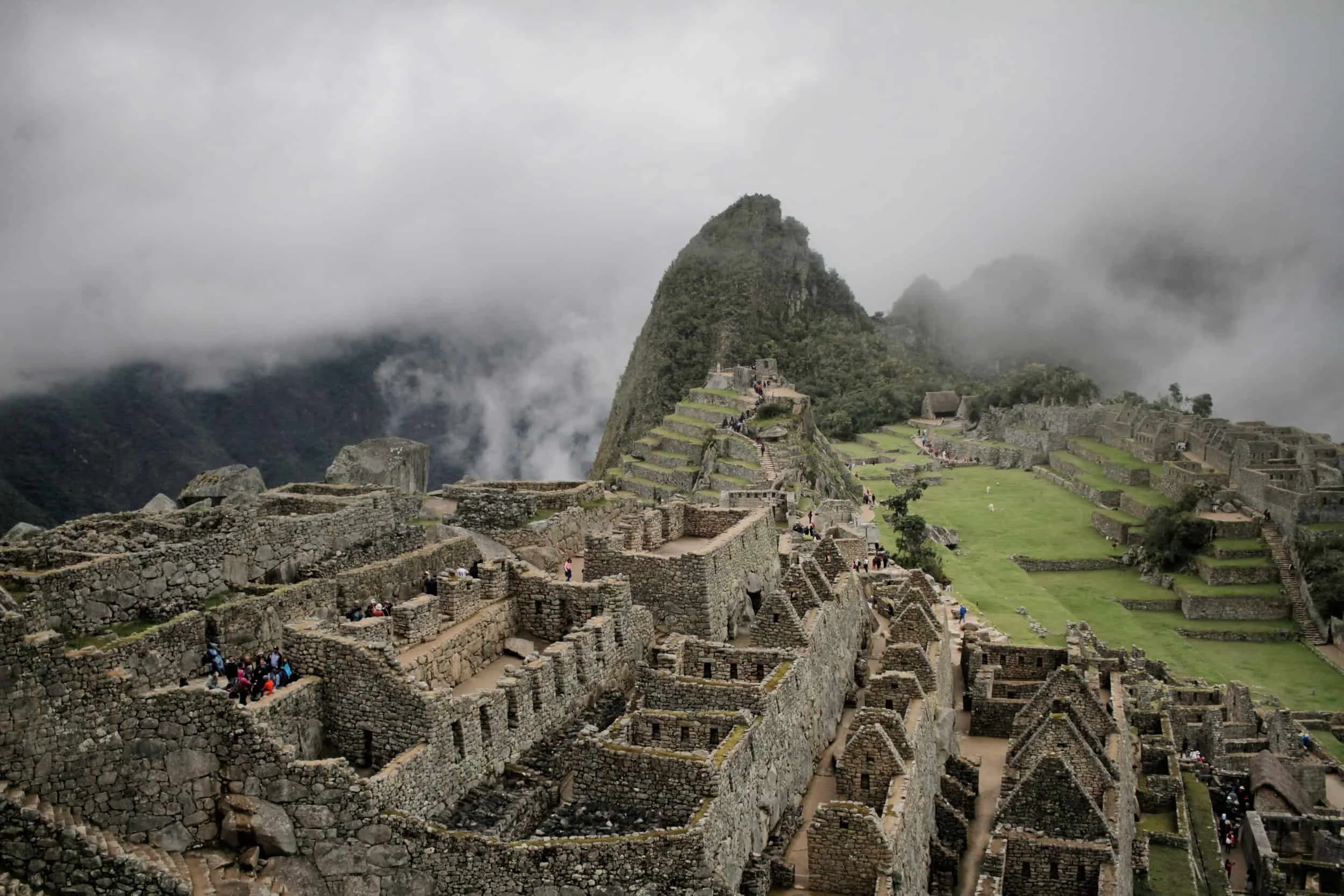 View from above Machu Picchu in Peru, ruins and green grass and clouds covering mountaintop