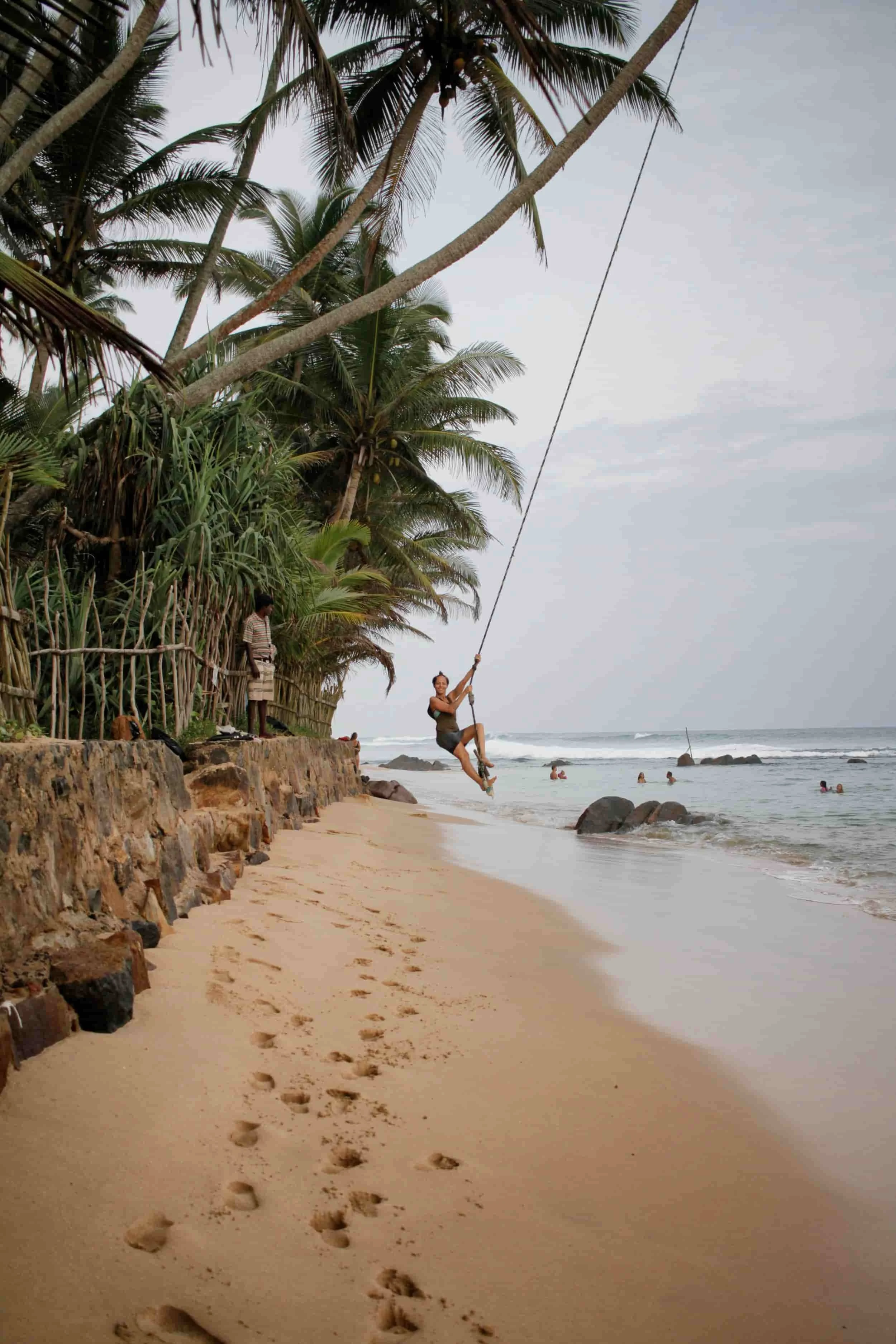 Girl swinging on rope swing at the beach in Mirissa, Sri LankaS