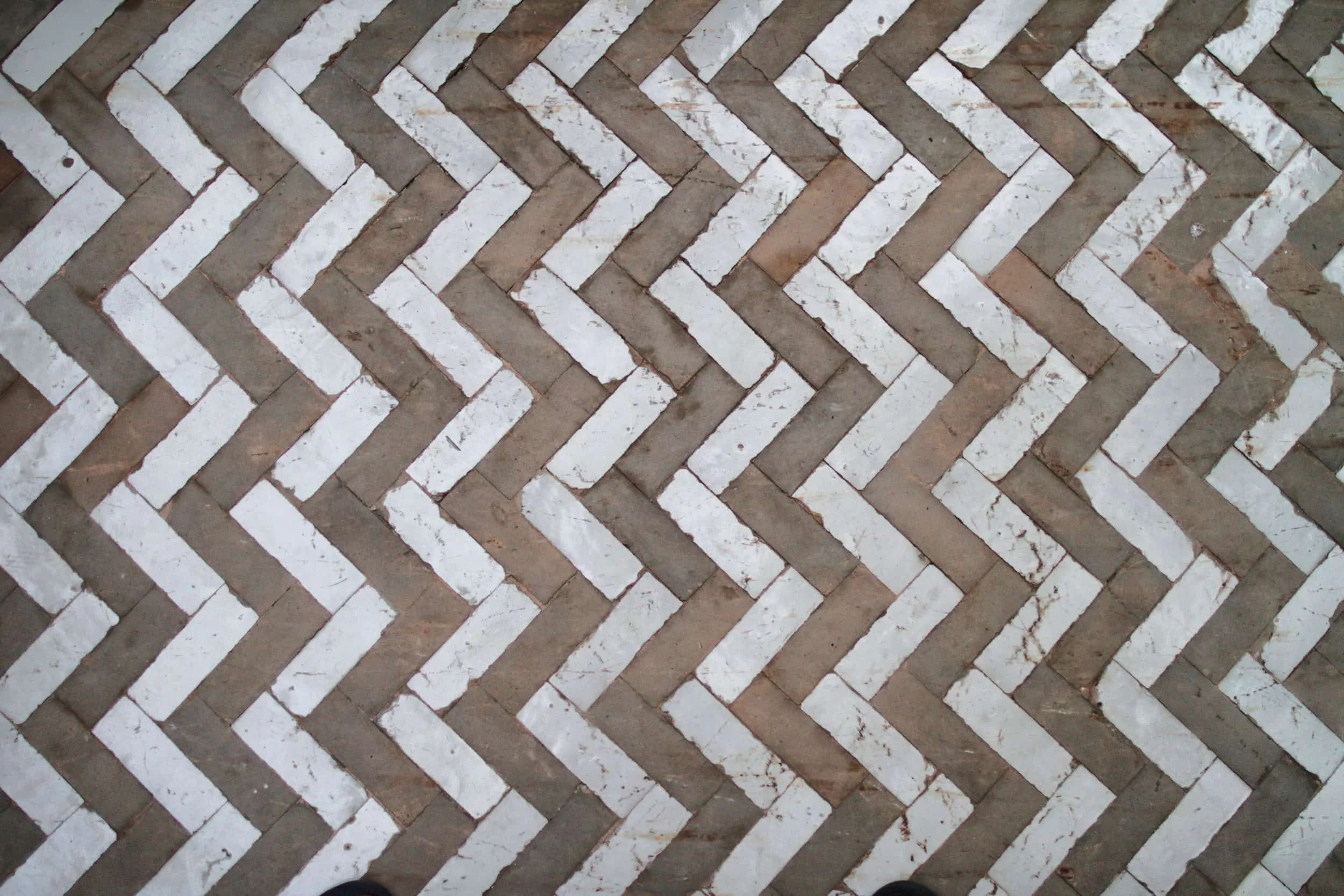 Herringbone pattern brick floor with alternating white and brown bricks.