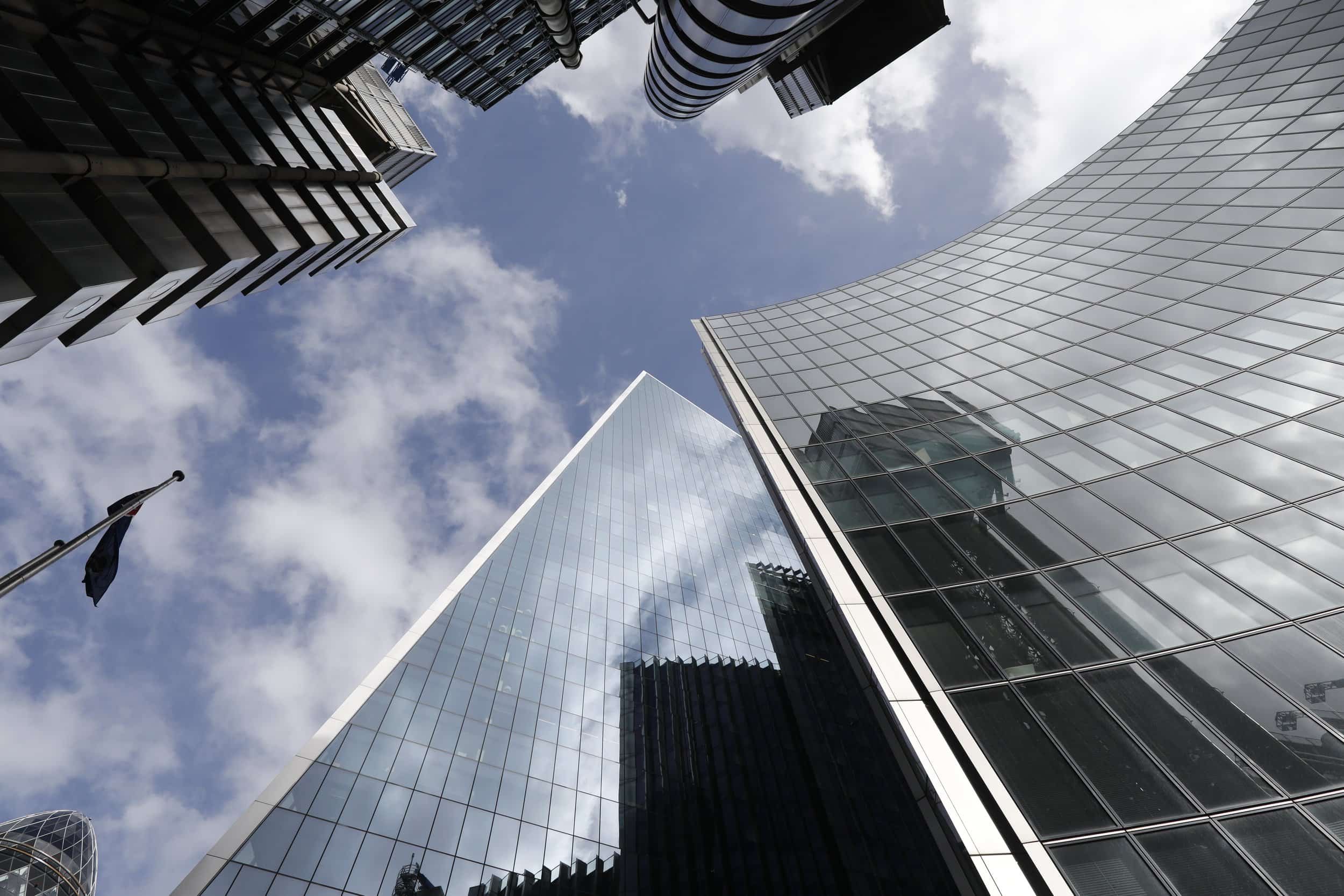 Looking up at tall modern glass skyscrapers against a partly cloudy sky.