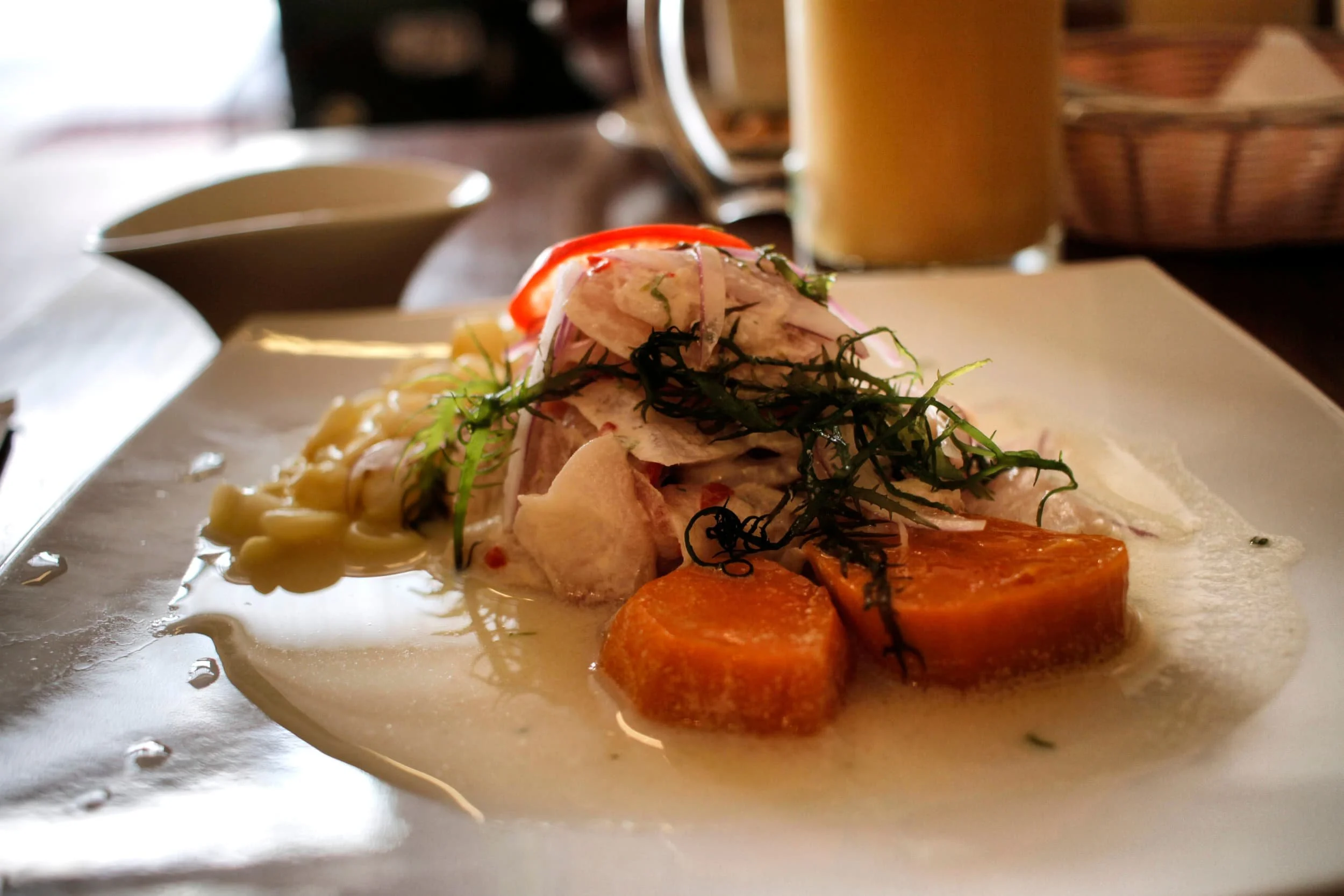 A plate of Peruvian ceviche with corn, sweet potato, seaweed and raw fish