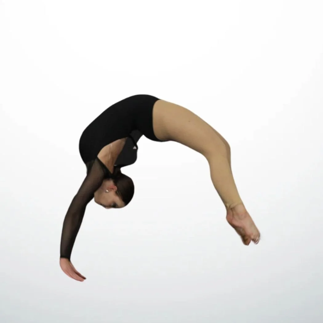 A young dancer wearing a black leotard and tan tights performs a tumbling skill in midair against a white background.