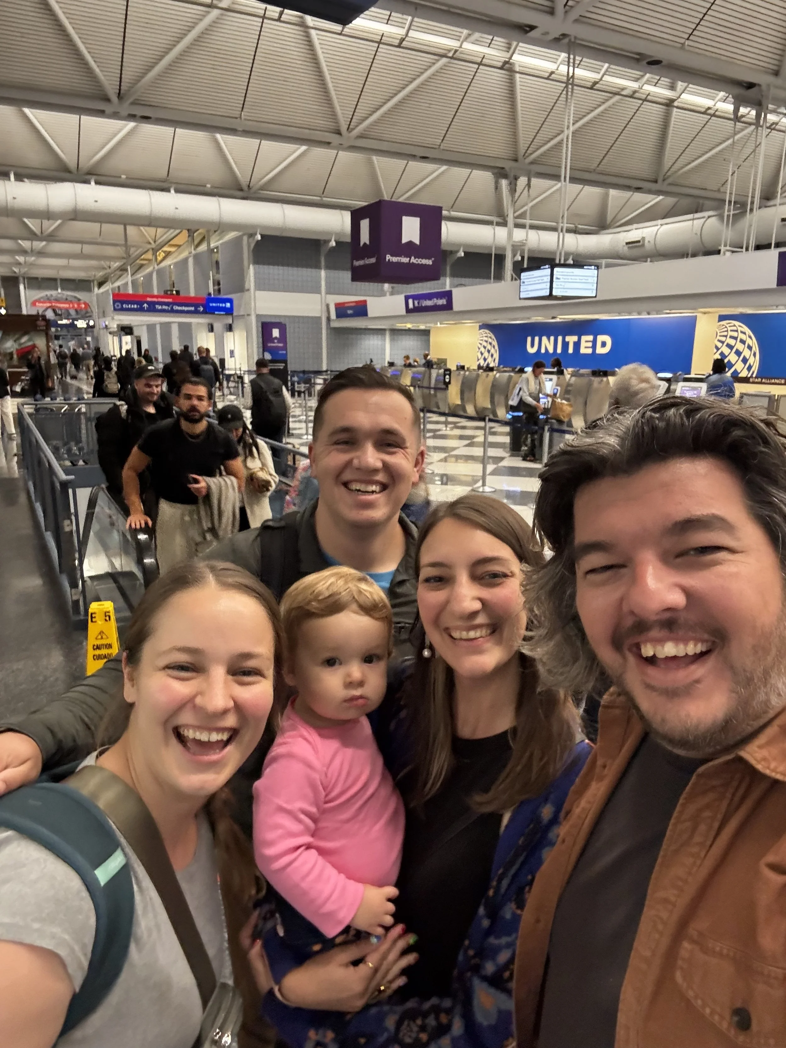 A group of friends smile in front of the United check in at O'Hare International Airport