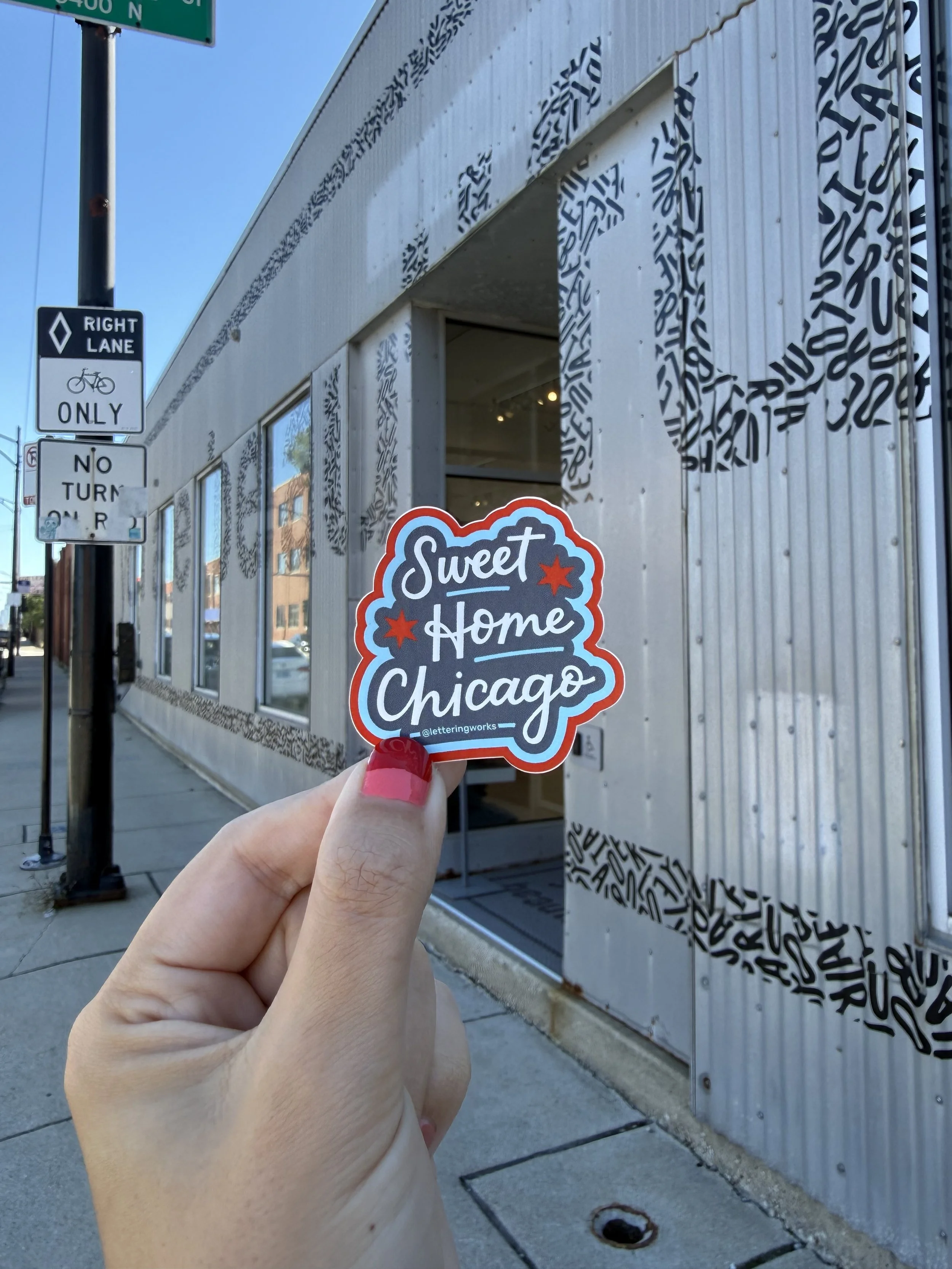 Chicago Artist Chelsie Tamms holds her Sweet Home Chicago sticker in front of the You Are Beautiful Gallery in Chicago
