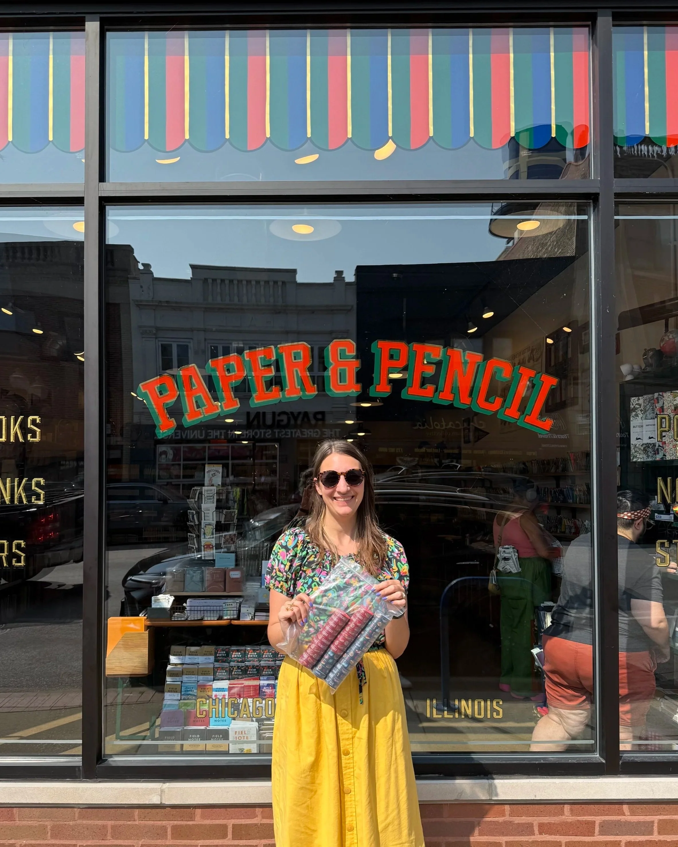 Artist Chelsie Tamms stands in front of Paper & Pencil with a bag full of Chicago washi tape she is delivering