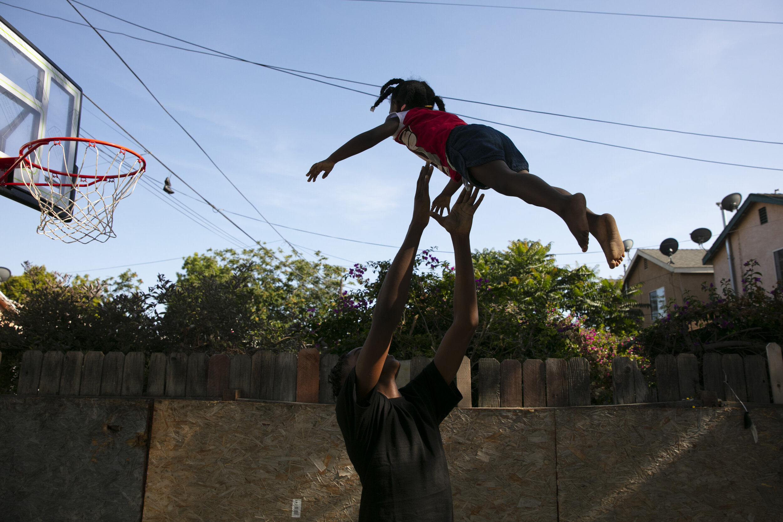  James Posey III, 14, tosses a neighbor's kid in the air while playing with her in the Watts neighborhood of Los Angeles, Monday, June 15, 2020. Watts has long been associated with deadly and destructive rioting in 1965. This summer when widespread m