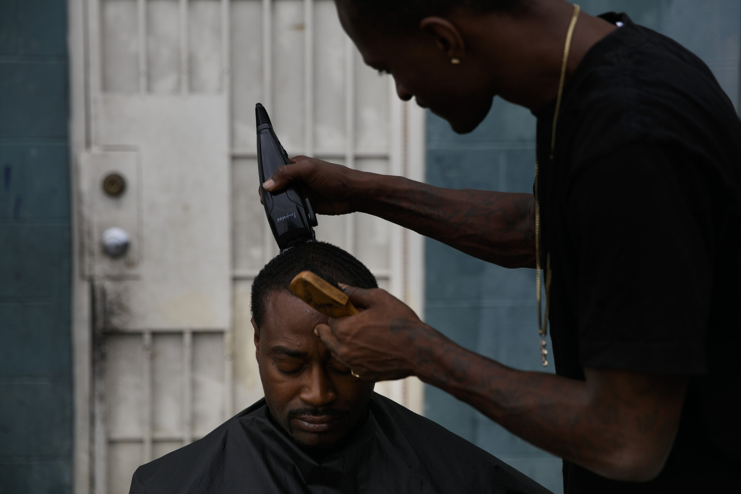  Eric Frierson, 37, gets an haircut from Kenneth Cox, 32, outside an apartment building at the Imperial Courts housing project in the Watts neighborhood of Los Angeles, Wednesday, June 17, 2020. Frierson laments losing focus on becoming a good athlet