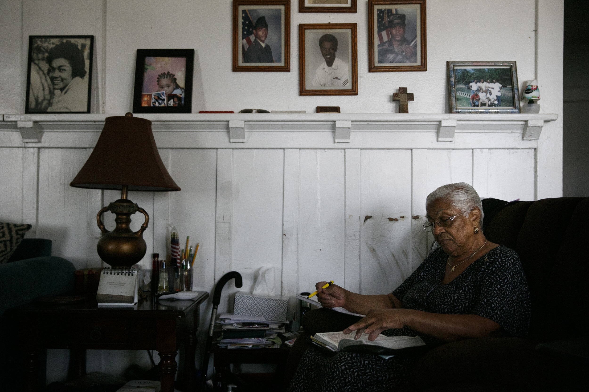  Lavarn Young, 81, reads her bible in the living room of her home as framed photos of herself, far left, and relatives adorn a wall Tuesday, July 14, 2020, in the Watts neighborhood of Los Angeles. Young, who moved to Watts from Texas in 1946, said s