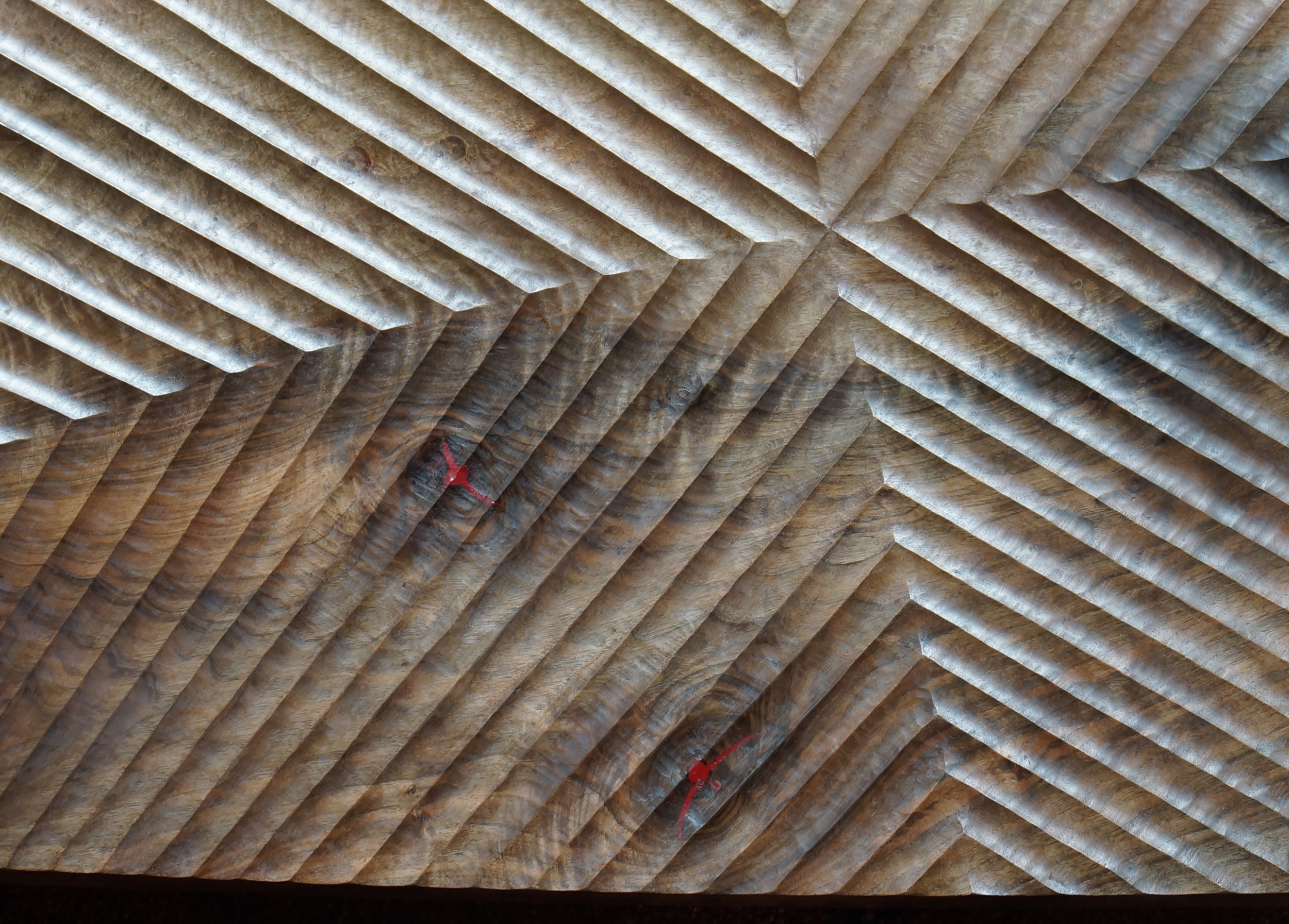 A large panel turned and carved with an arced Chevron pattern. The holes are filled with red epoxy.