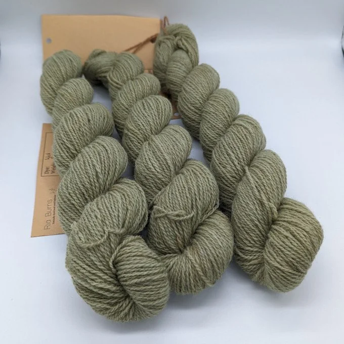 Cream-colored yarn with orange and red streaks, twisted into skeins.