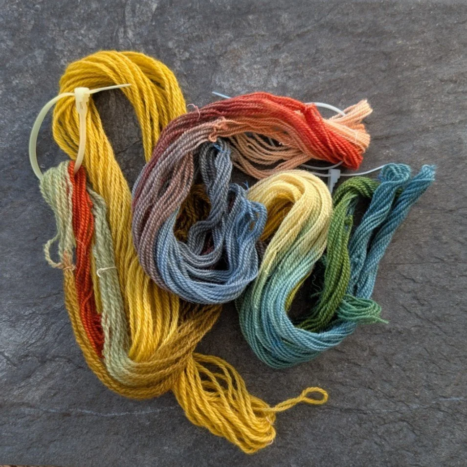 Cream-colored yarn with orange and red streaks, twisted into skeins.