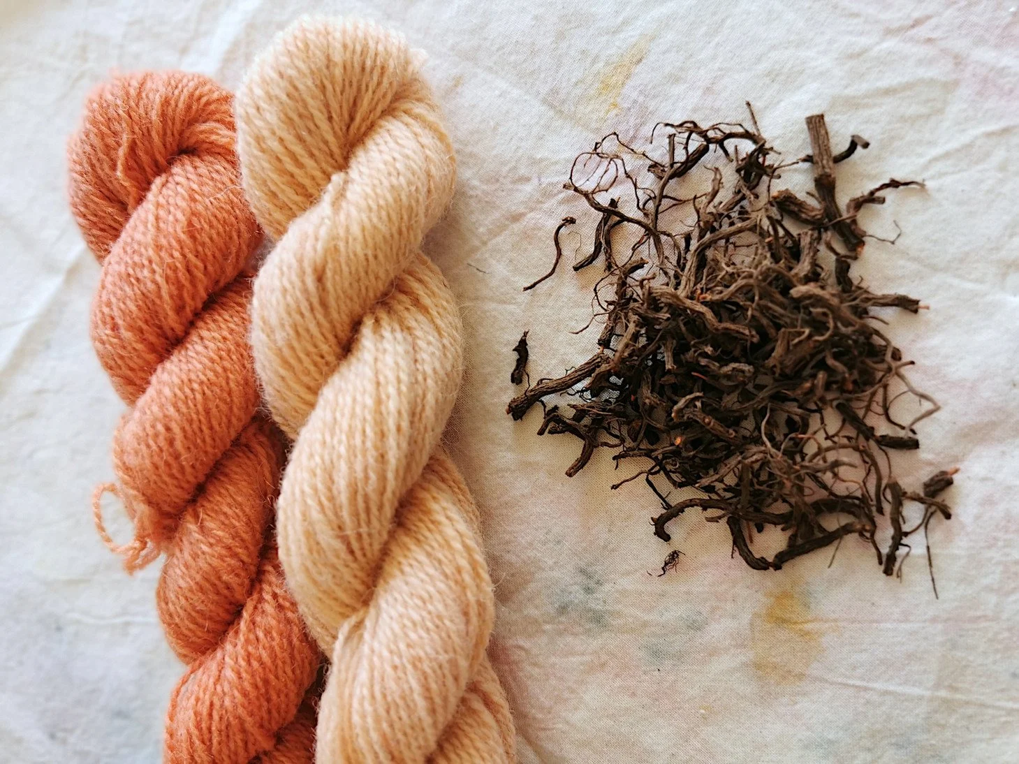 Cream-colored yarn with orange and red streaks, twisted into skeins.
