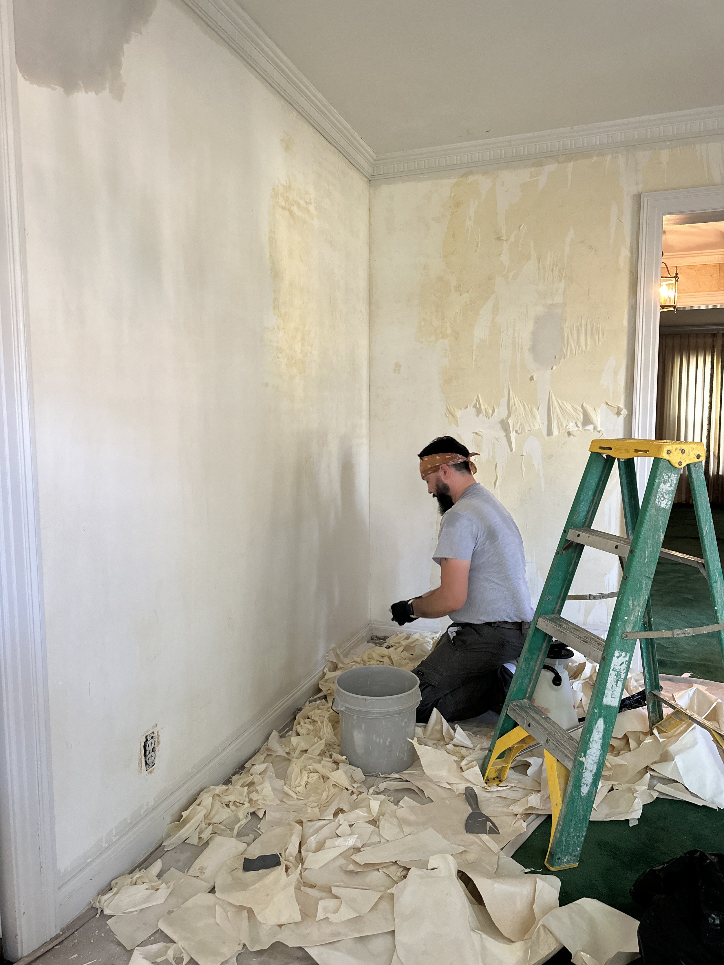 Removing wallpaper to prepare for new wallpaper restoration in an old home