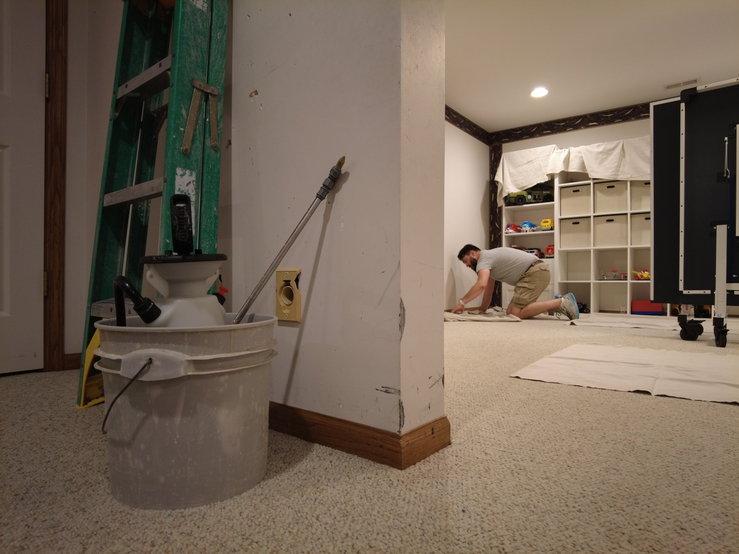 Wallpaper removal tools with a man removing wallpaper in the background of the photo. The PAper Puller Removing Wallpaper in Lincoln, Nebraska