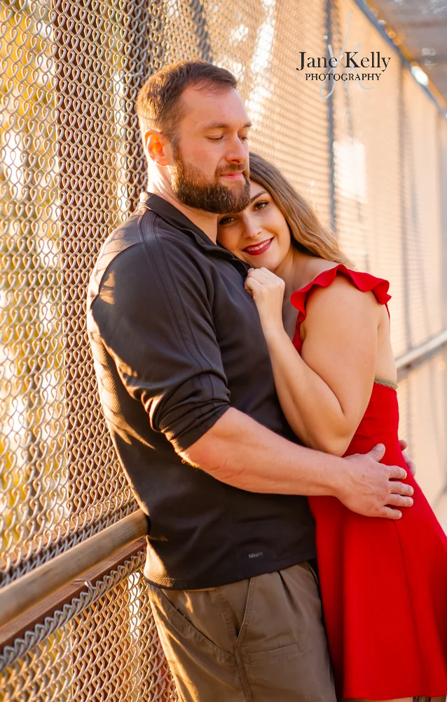 married couple cuddling on bridge