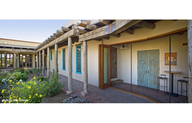 Portals and deep overhangs shade living spaces and link the home’s three separate structures—so the family experiences the outdoors as they move among rooms. This hallway opens via a foldable wall of windows to the courtyard, where xeric plants thrive on captured rain and recycled gray water.