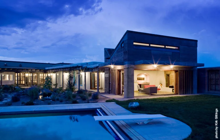 Two sides of the home’s family room open to the outside by way of retractable glass walls. Like the rest of the house, the swimming pool is heated by solar power; it is covered to minimize evaporation when not in use.