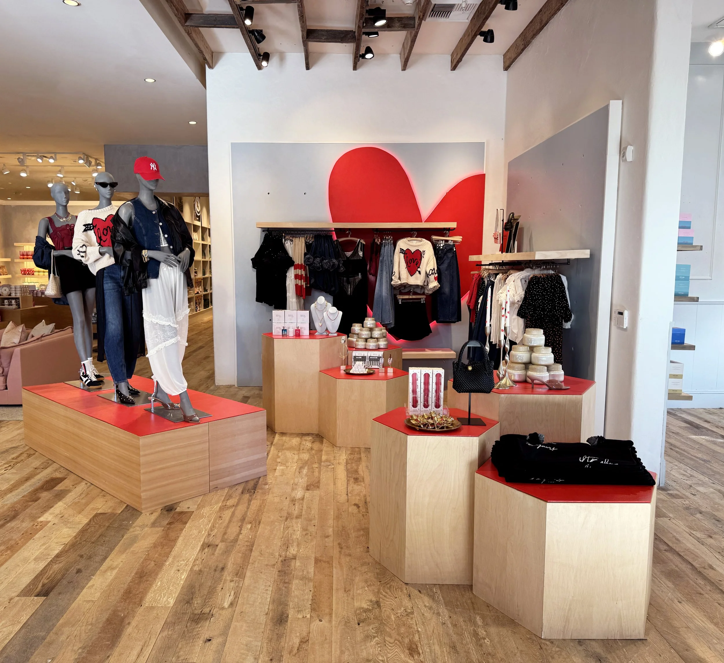    Anthropologie Spring ‘26 Interiors:    Valentine’s shop made up of wooden shapes cut, and painted red. Heart haloed in red light. 