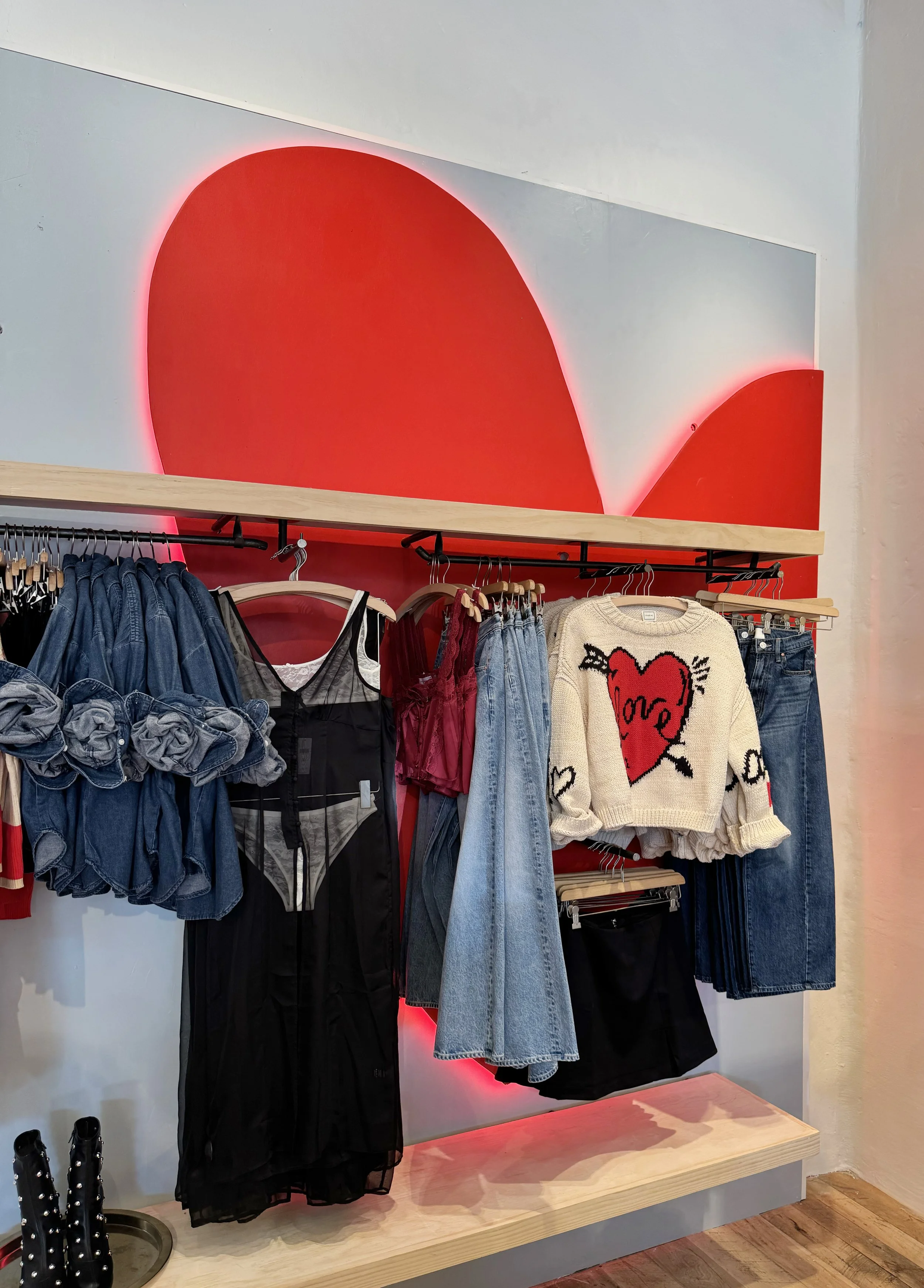    Anthropologie Spring ‘26 Interiors:    Valentine’s shop made up of wooden shapes cut, and painted red. Heart haloed in red light. 