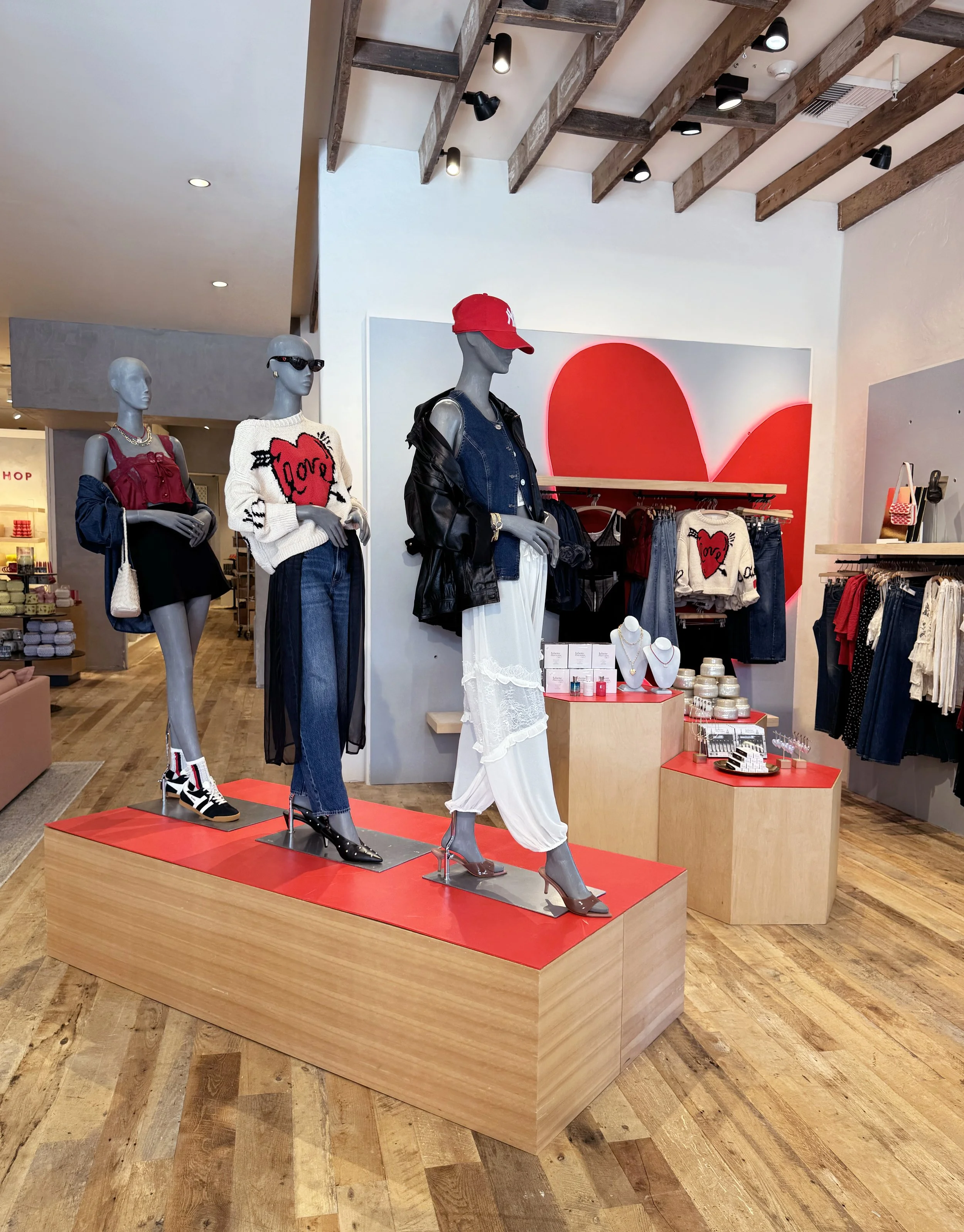    Anthropologie Spring ‘26 Interiors:    Valentine’s shop made up of wooden shapes cut, and painted red. Heart haloed in red light. 