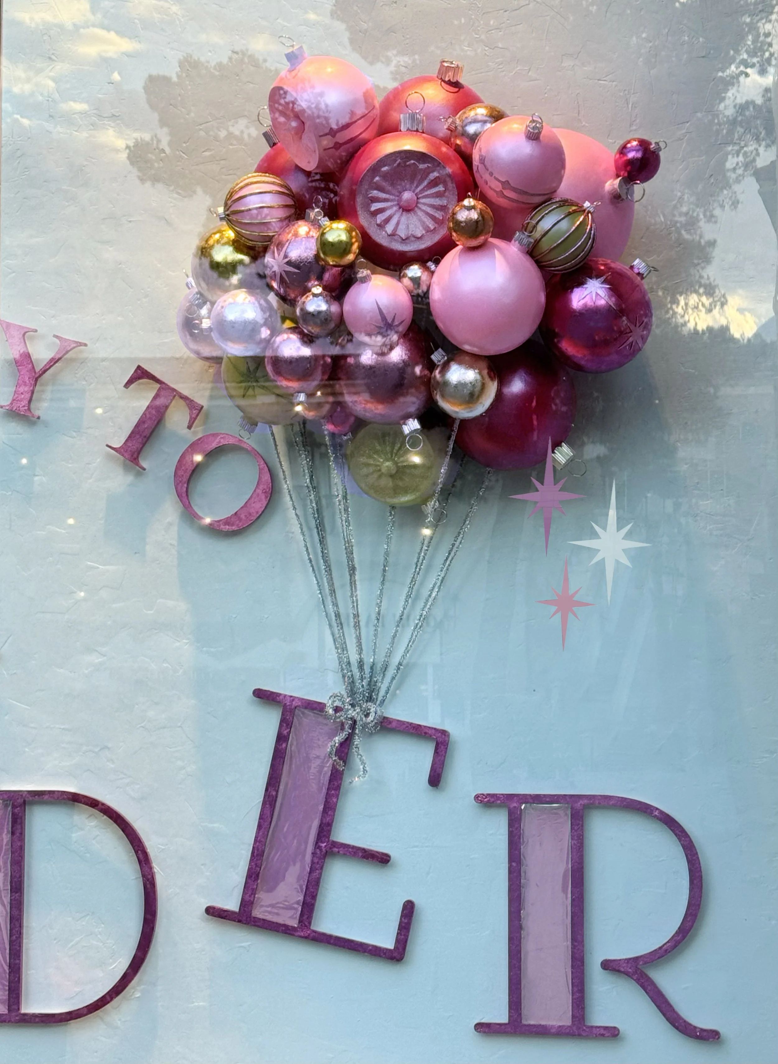    Anthropologie Holiday ‘25 Window:    Ornaments sculpted from foam and plaster. On glass painted sparkles. Sign laser cut and pink foiled. 