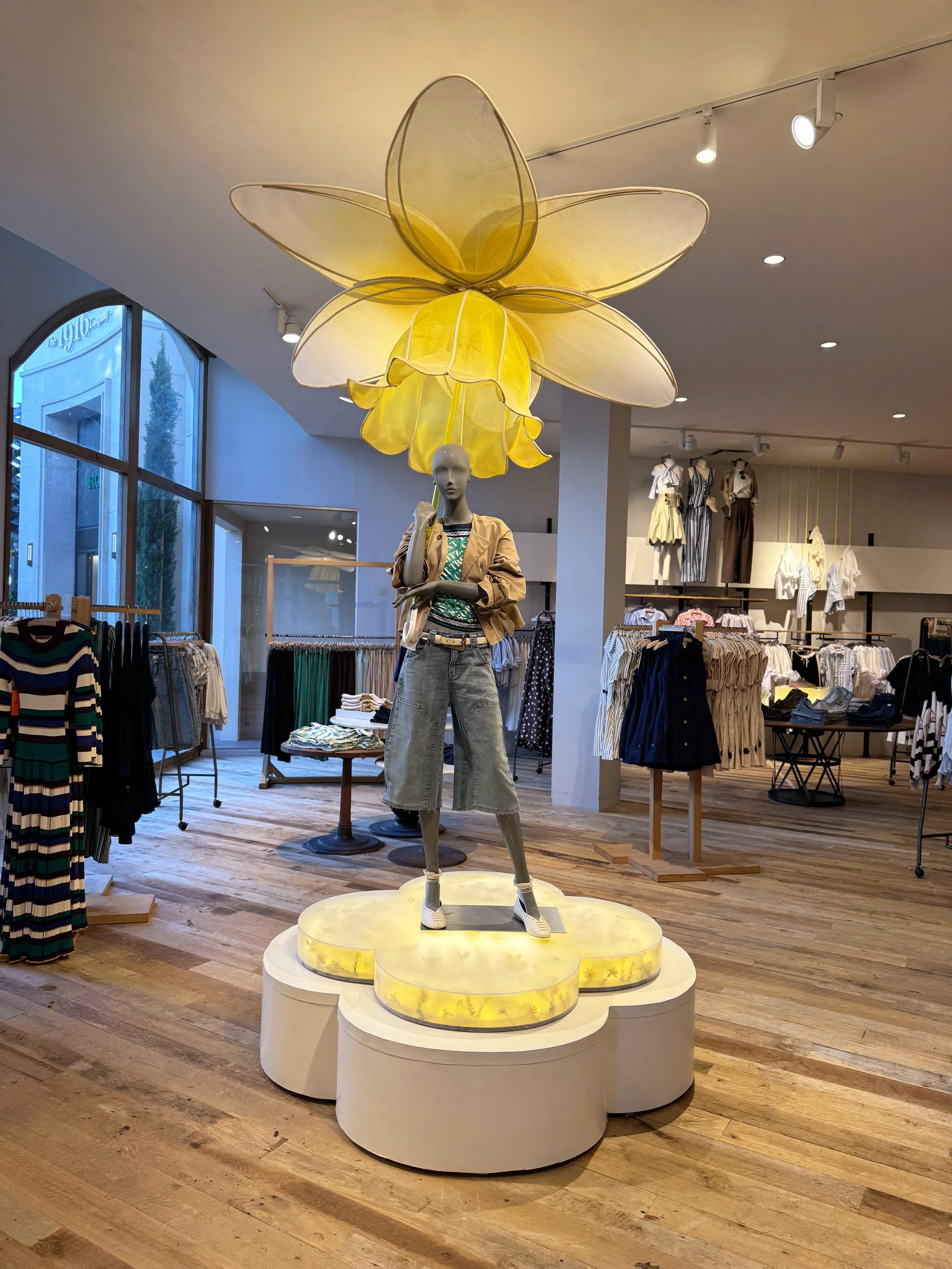    Anthropologie Spring ‘26 Interiors:    Daffodil umbrella made from painted silk screen, and soaked reed. Lit frosted risers, filled with hand dyed flowers . 