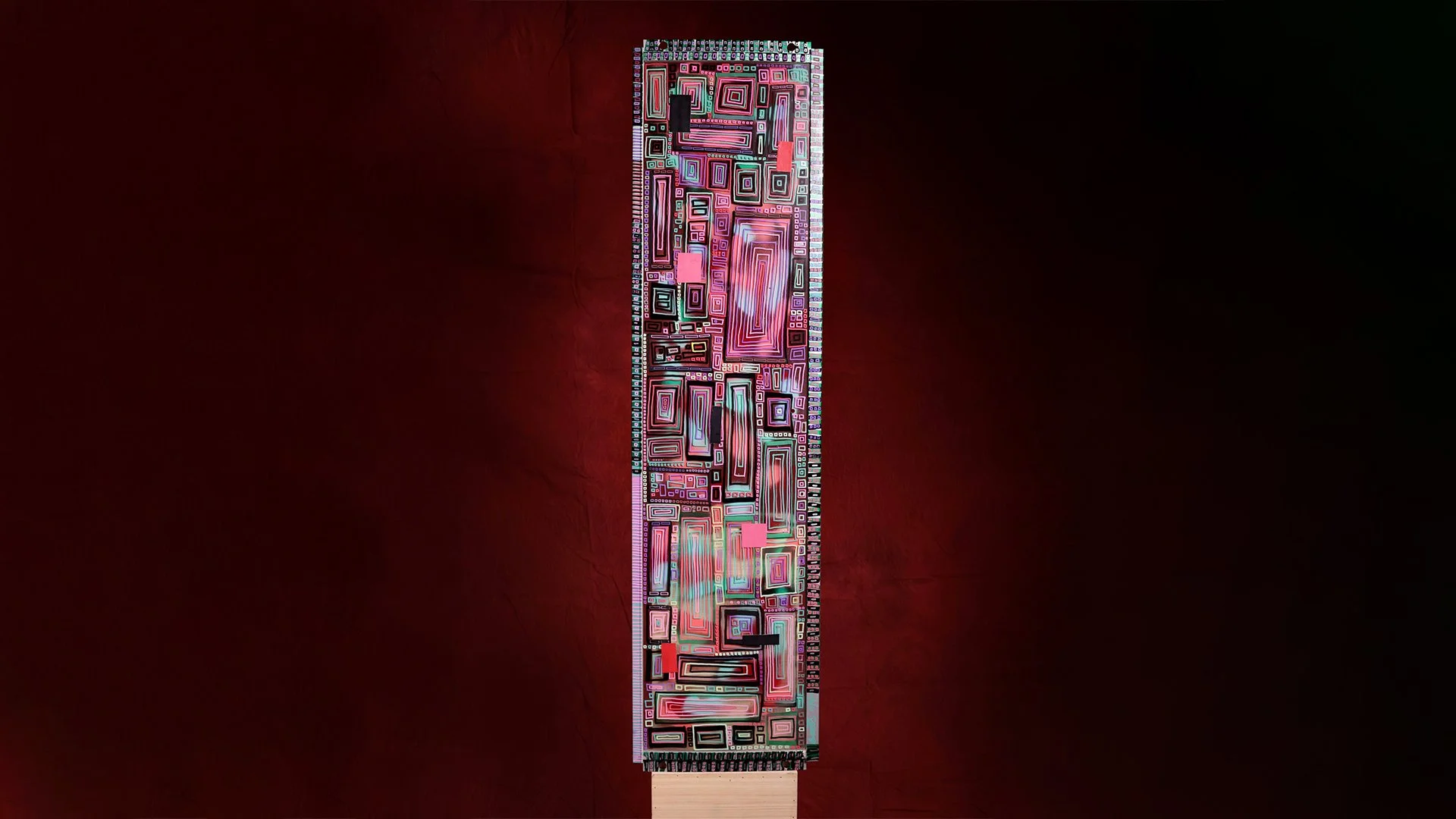 A tall, rectangular, abstract artwork with geometric patterns and bright colors, mounted vertically on a dark red background.