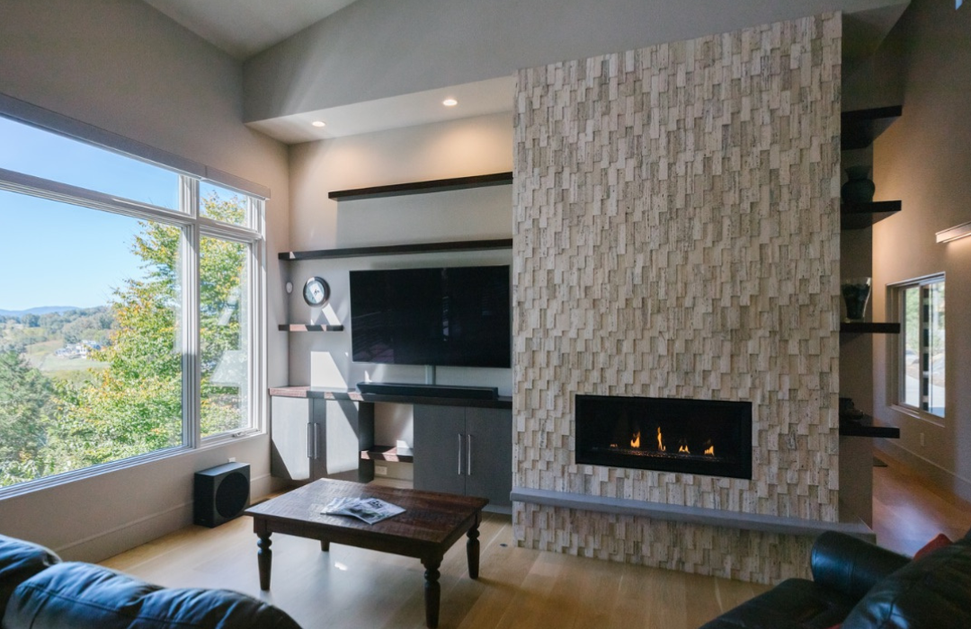 Textured stacked stone fireplace tower beside a window with a mountain view