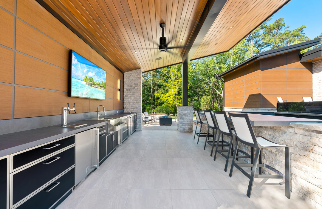Sleek outdoor kitchen with dark stainless steel cabinets, a gray sintered stone countertop, on a tiled deck