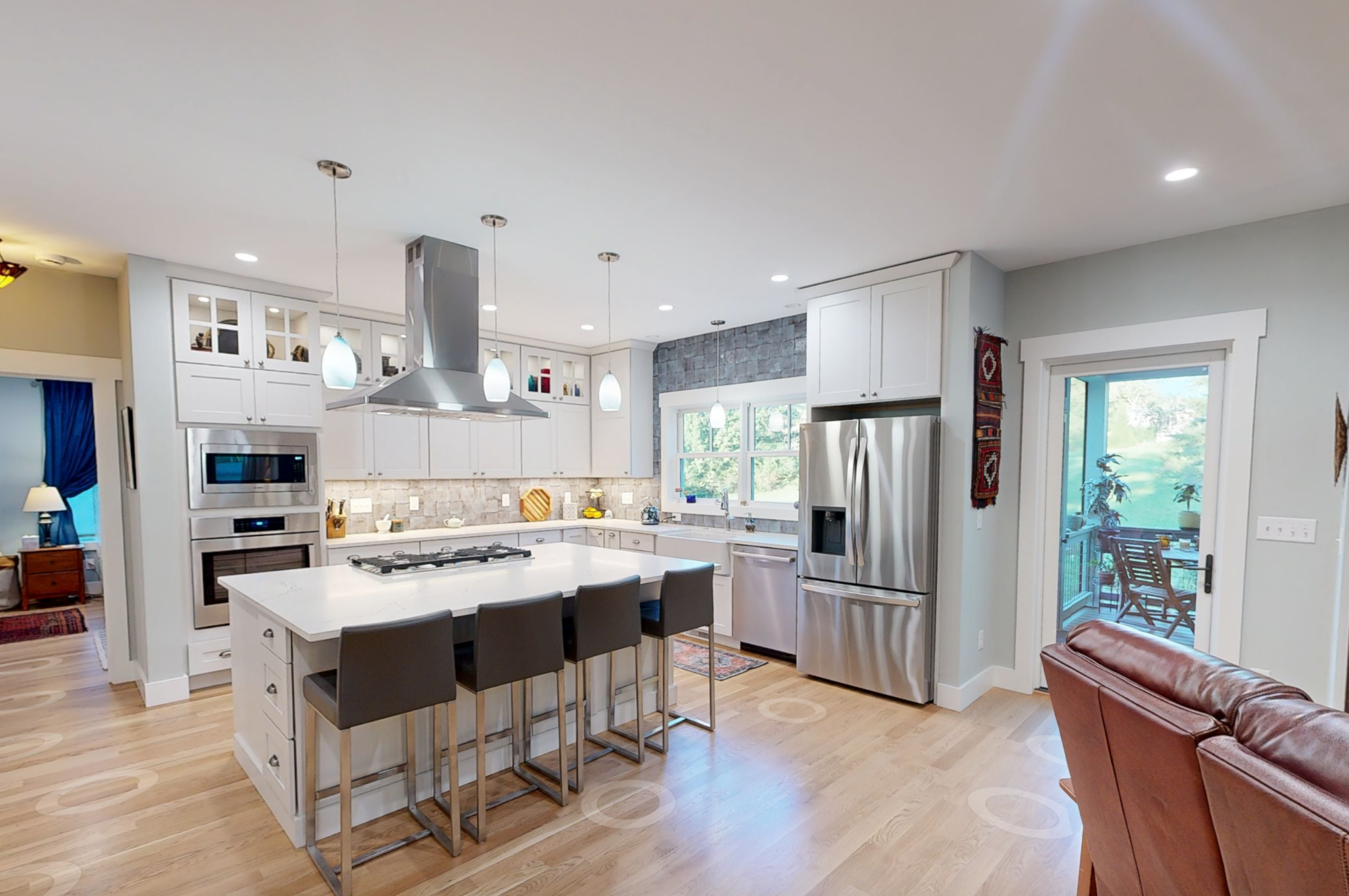 White Wellborn Premier Series kitchen cabinets with Cambria countertops, stainless steel appliances, center island with bar seating, and hardwood floors in a gold award-winning custom craftsman home in Weaverville, NC.