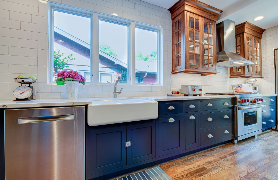 Kitchen design featuring natural cherry wood upper cabinets with glass doors, navy blue painted lower cabinets, white subway tile backsplash, and farmhouse sink