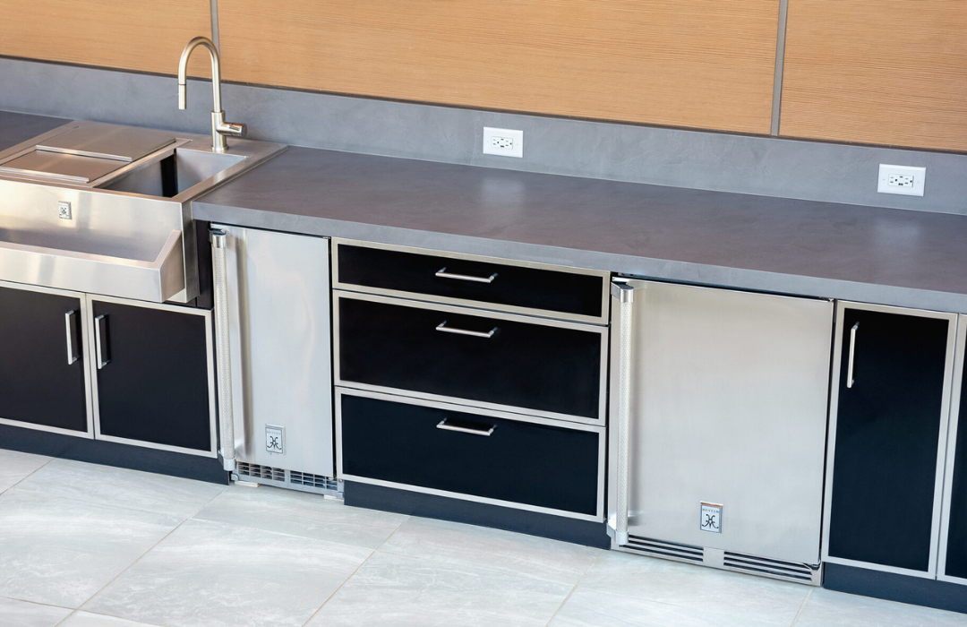 Danver stainless steel outdoor kitchen cabinets in black with integrated refrigerator drawers, sink, and gray countertop