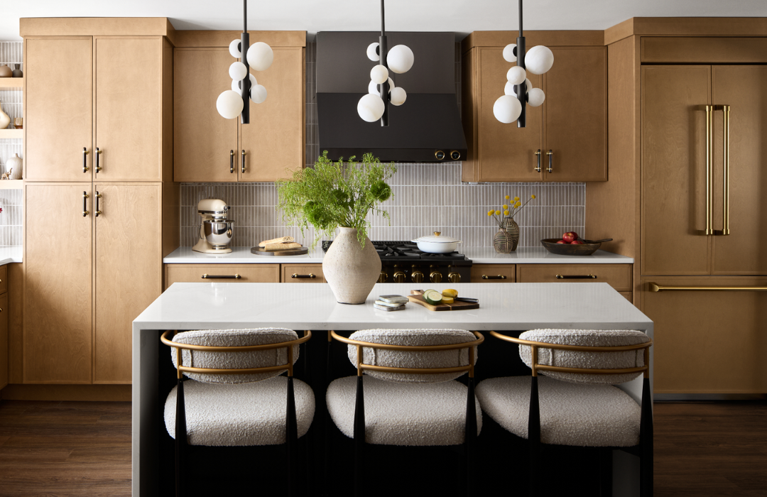 Warm natural maple kitchen cabinets with white quartz countertops, fluted tile backsplash, modern globe pendant lights, brass hardware demonstrating how quiet luxury complements mountain home aesthetics