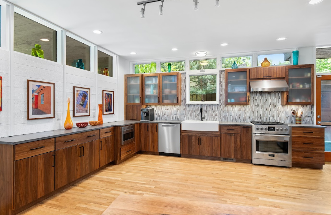 Full wood kitchen featuring walnut cabinets throughout with frosted glass upper doors, patterned tile backsplash, and natural wood flooring in bright, open Asheville kitchen