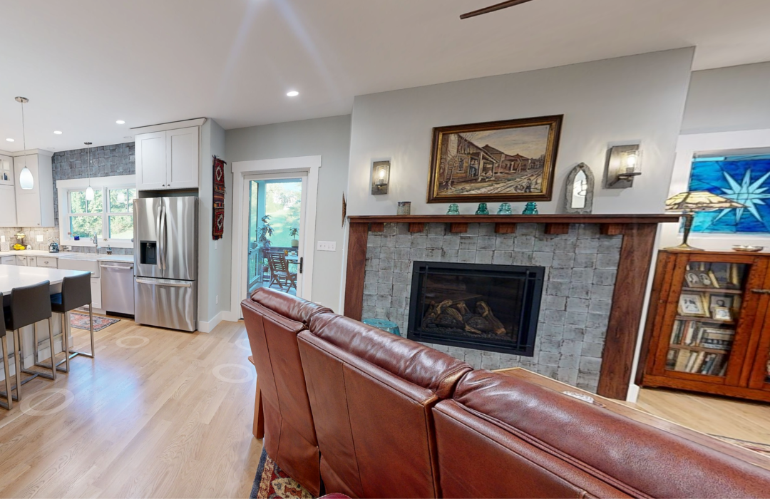 Wood mantel with framed art and decor above a gray tile fireplace surround