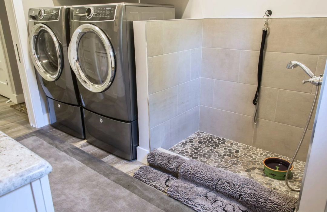 Laundry room with dog washing station featuring tiled walls and pebble floor drain