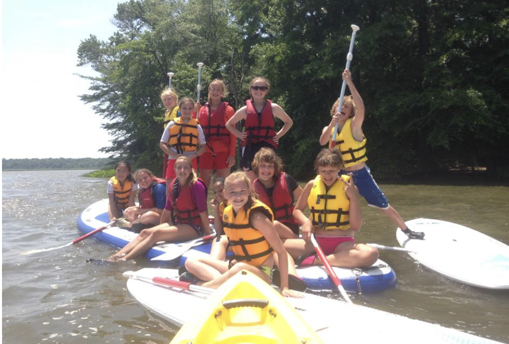 Children's SUP Party - a group of children and young people on stand up paddleboards posing for a picture on the water