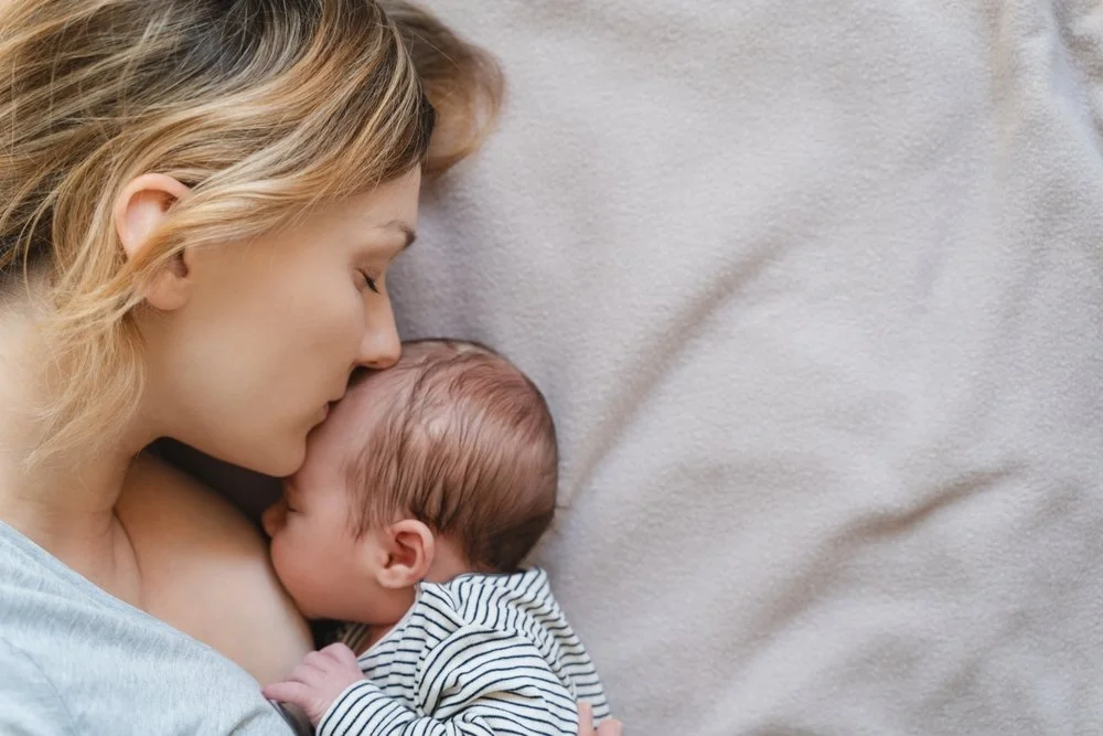 mother kissing her baby on the forehead
