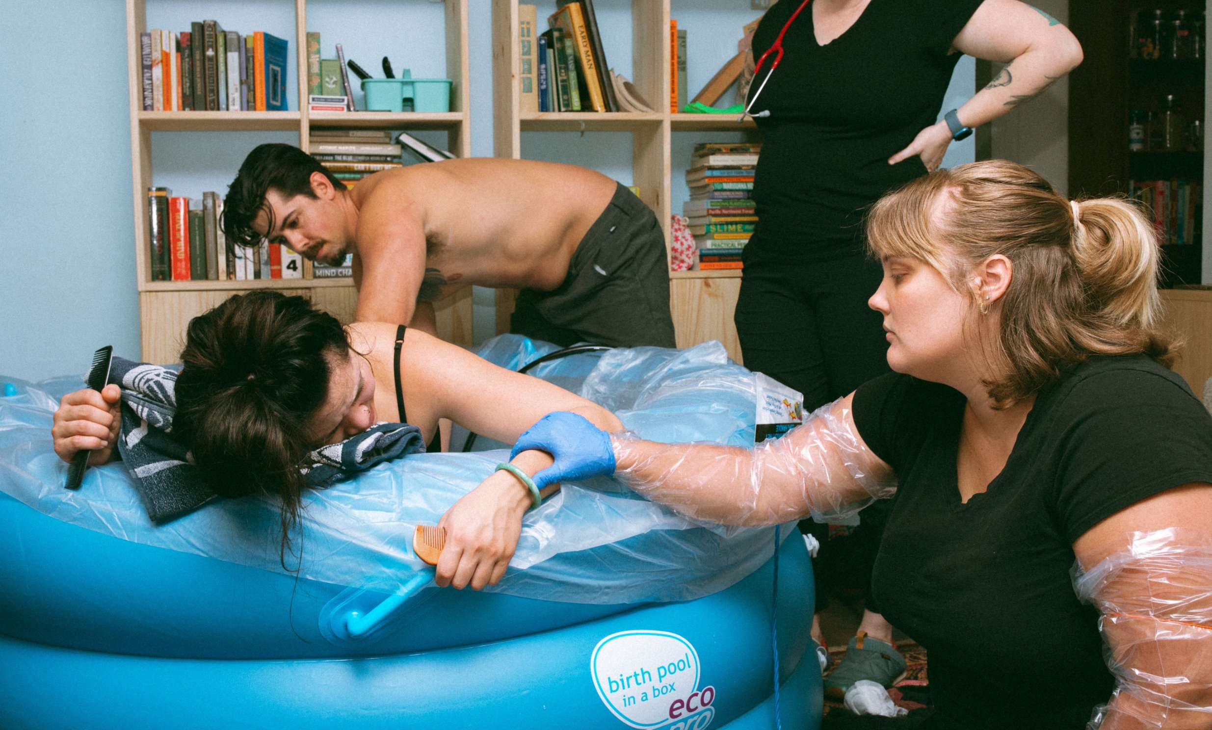 midwife holding onto pregnant woman's arm as she gives birth