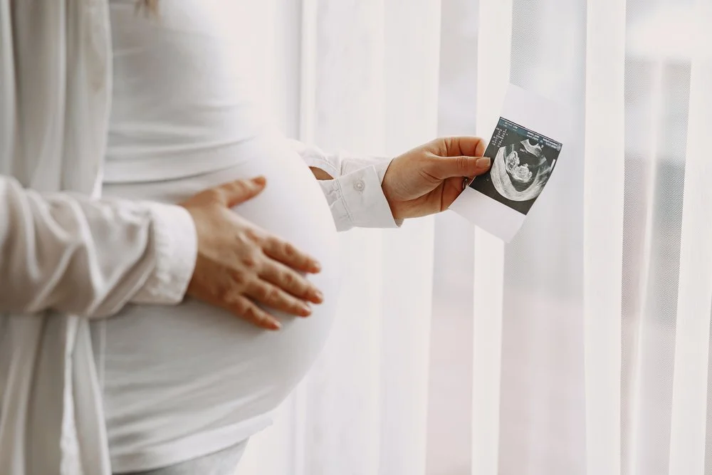 pregnant woman looking at a picture of her baby