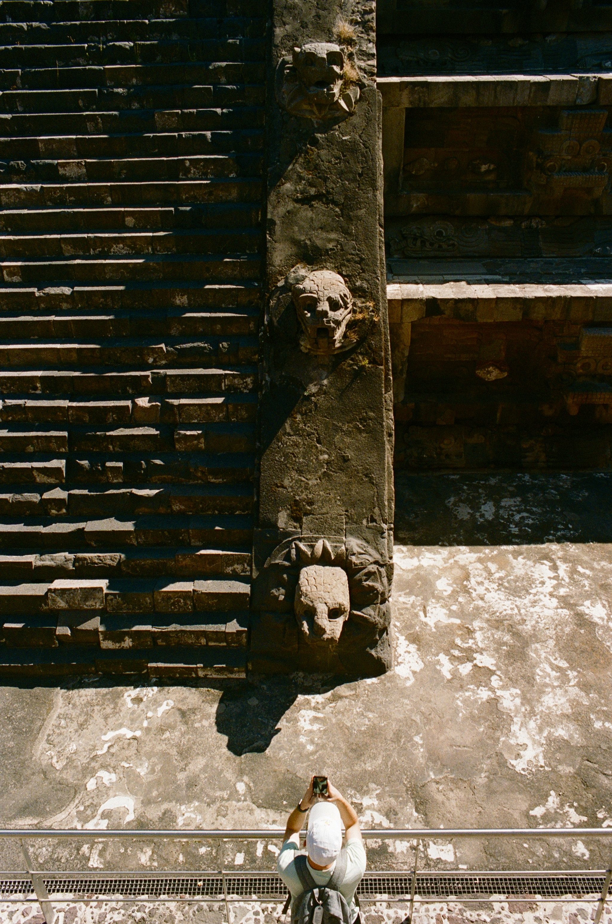 Charlie Michael Photography | Award Winning City Photography | LinkedIn | BCG | 35mm Kodak Portra 400 Nikon | Tourist taking photos of ancient stone goblin faces at teotihuacan mexico city ancient site aztec empire.jpg