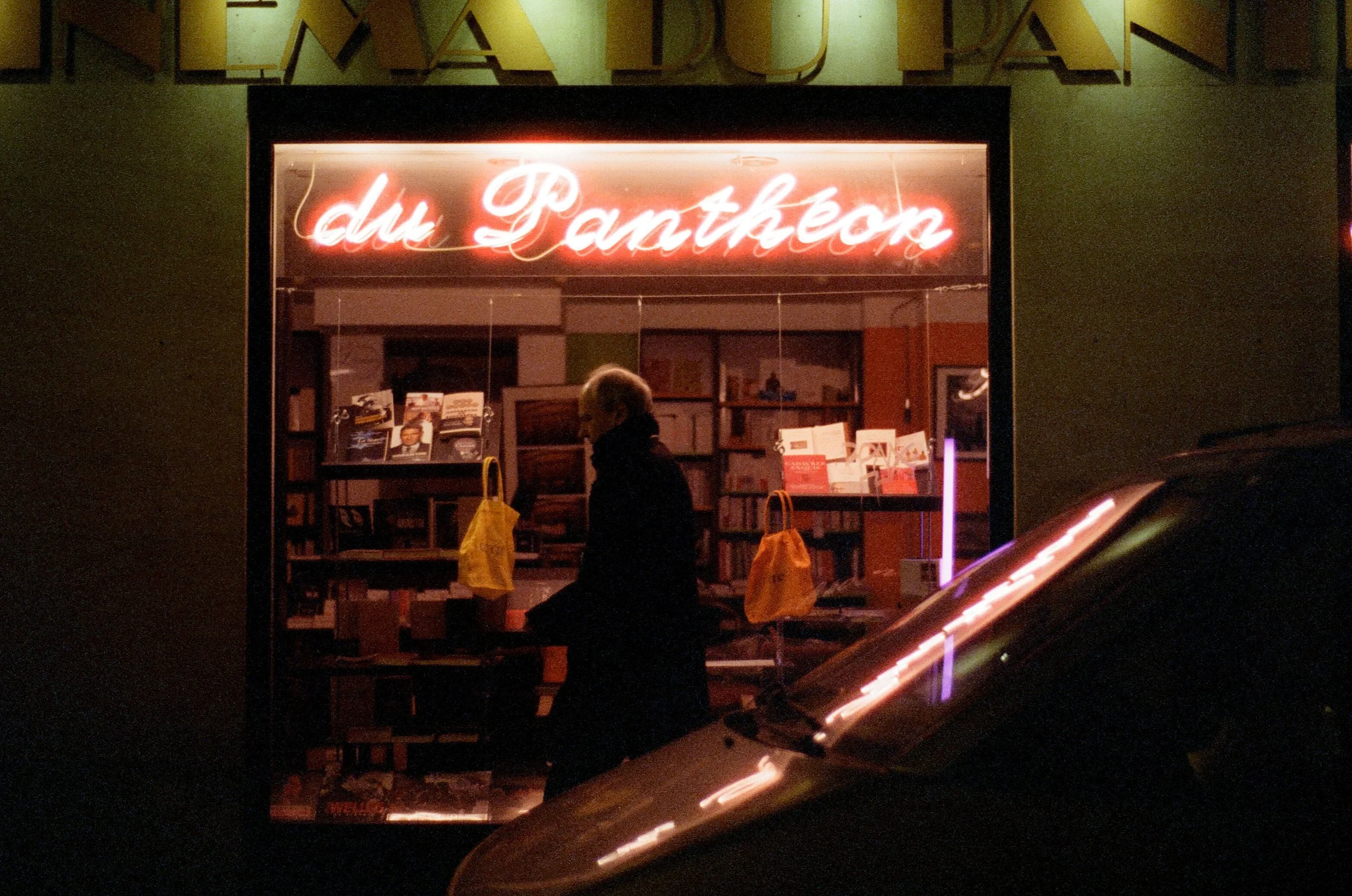 Charlie Michael Photography | Award Winning City Photography | LinkedIn | BCG | 35mm Kodak Portra 400 Nikon | Nighttime scene close to the pantheon in Paris France a man walks past a neon sign.jpg